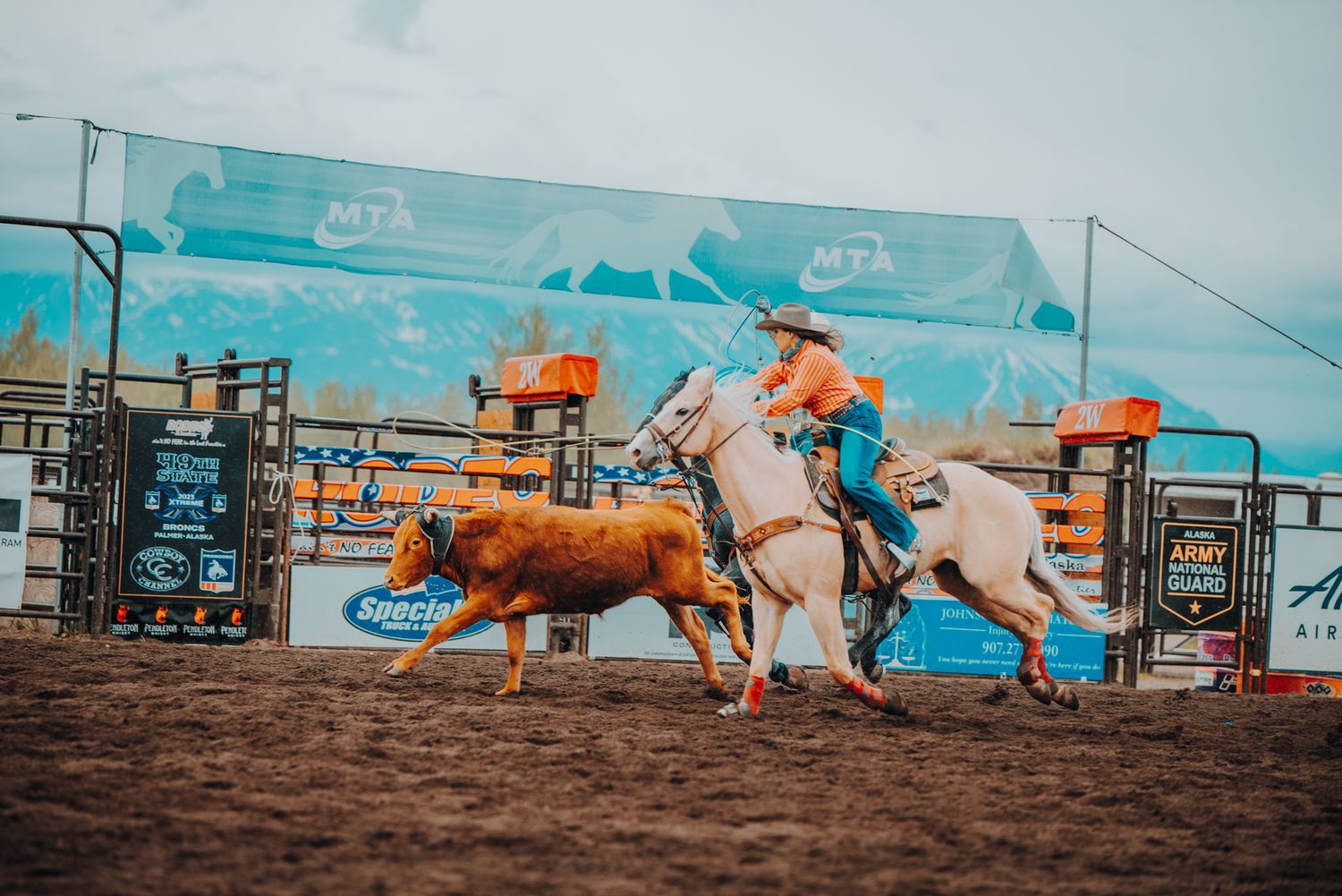 Team roping action with riders pursuing steer in western rodeo arena.