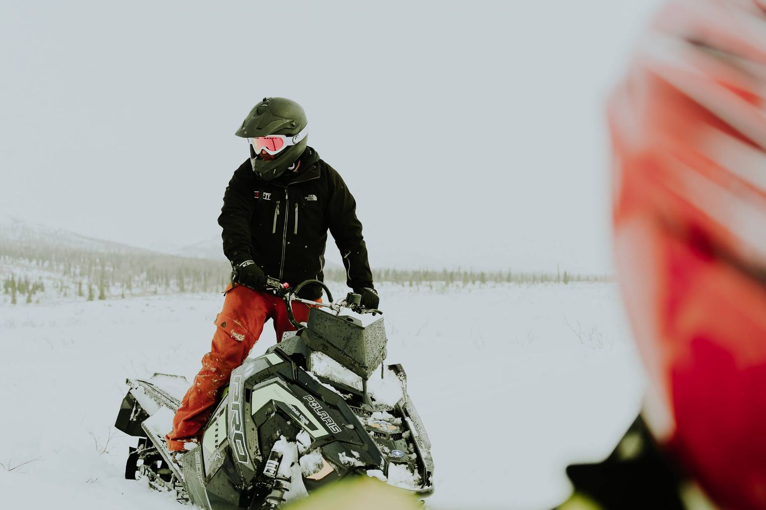 Winter sports enthusiasts riding snowmobiles through snowy terrain.