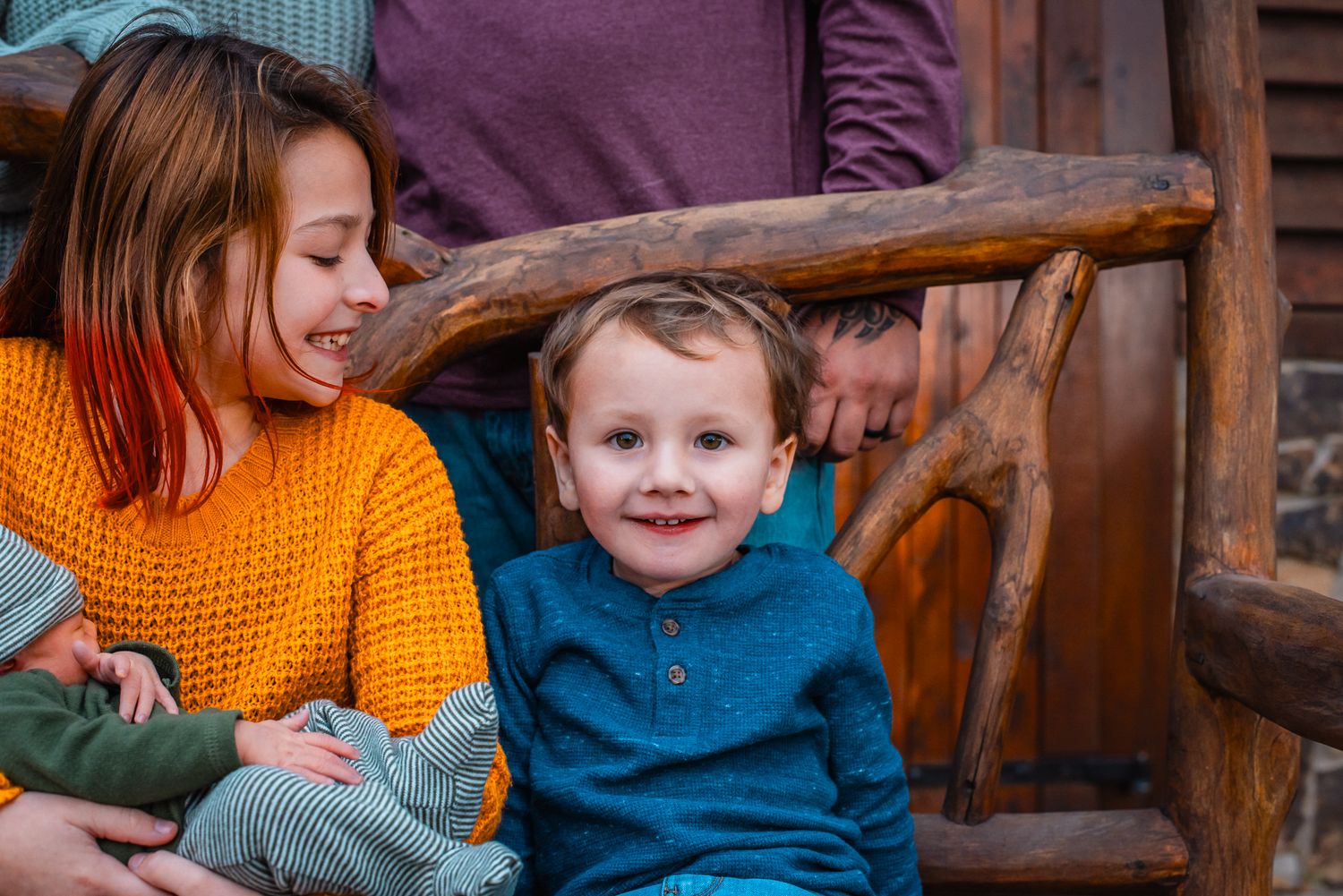 Family sitting together on a rustic wooden bench sharing playful moments.