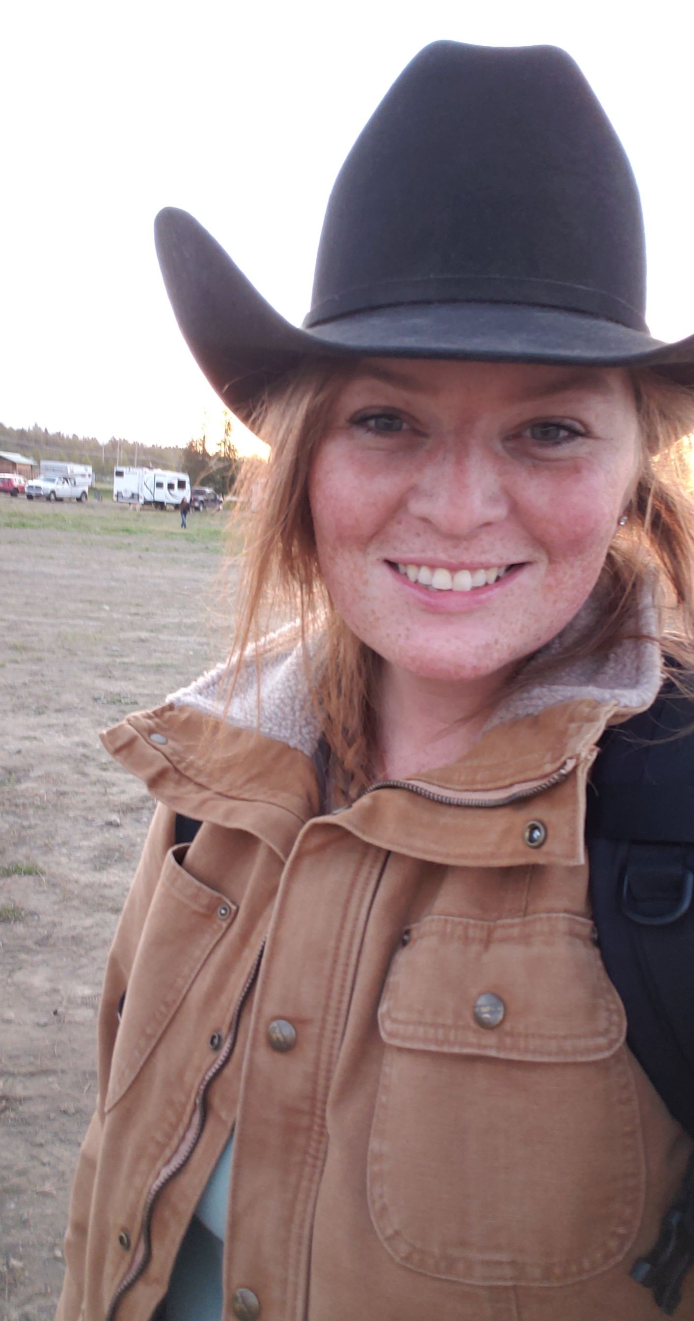 Person wearing a brown jacket and cowboy hat in an outdoor setting.