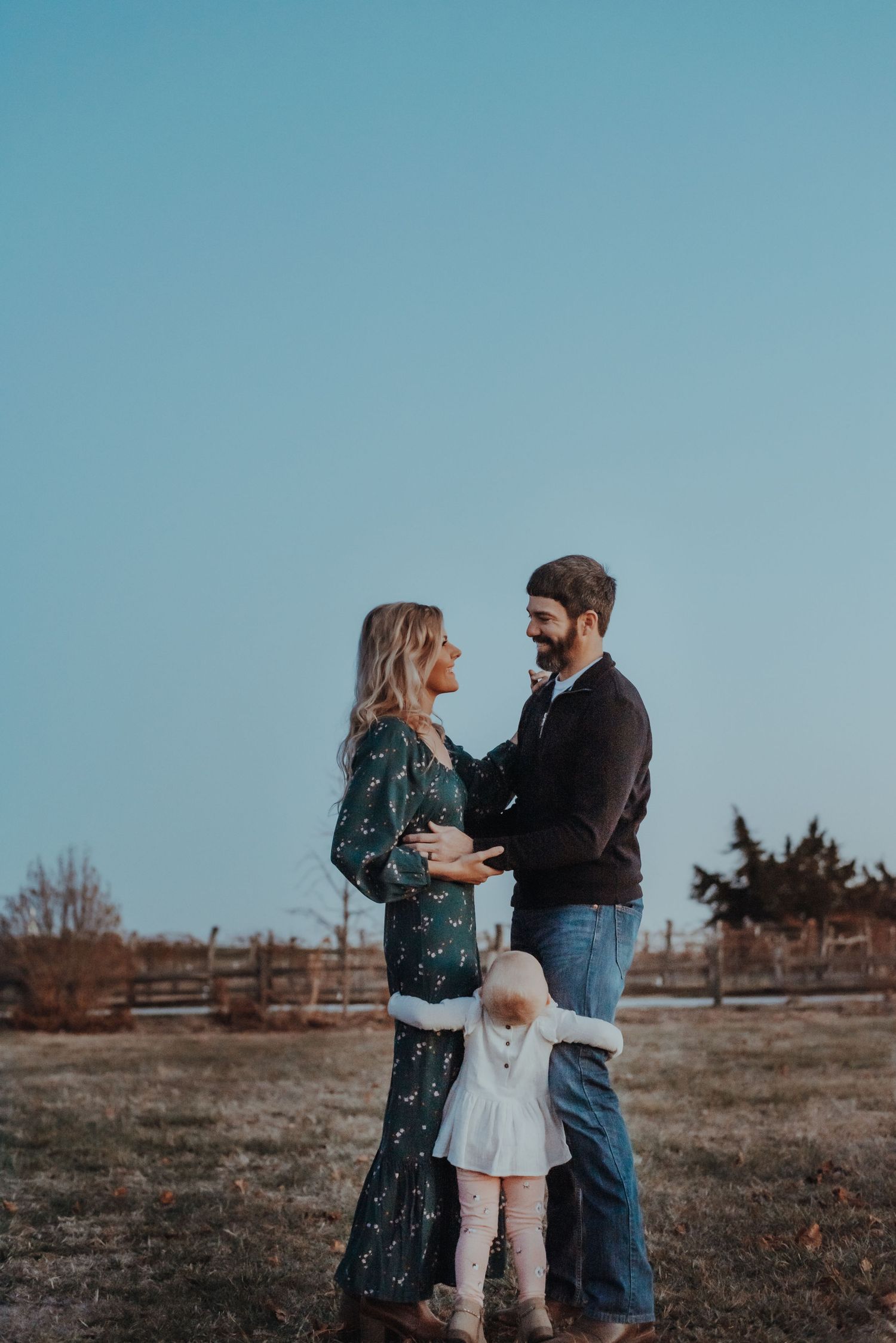 A couple shares an intimate moment in a field during golden hour.