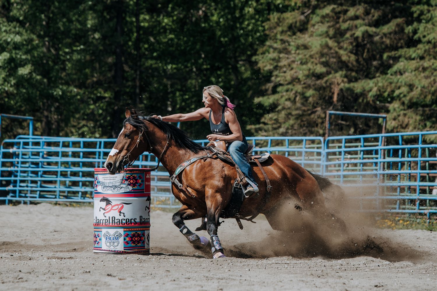 Barrel racing action shot at a rodeo arena with blue gates.