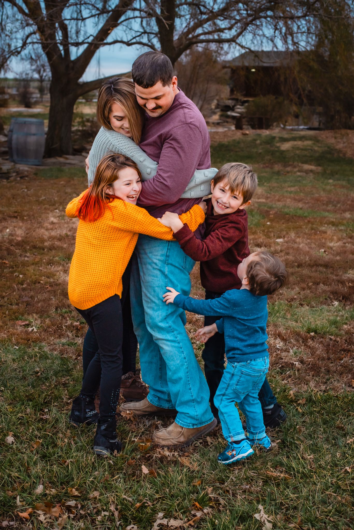Family playing and hugging together on grass during autumn season.