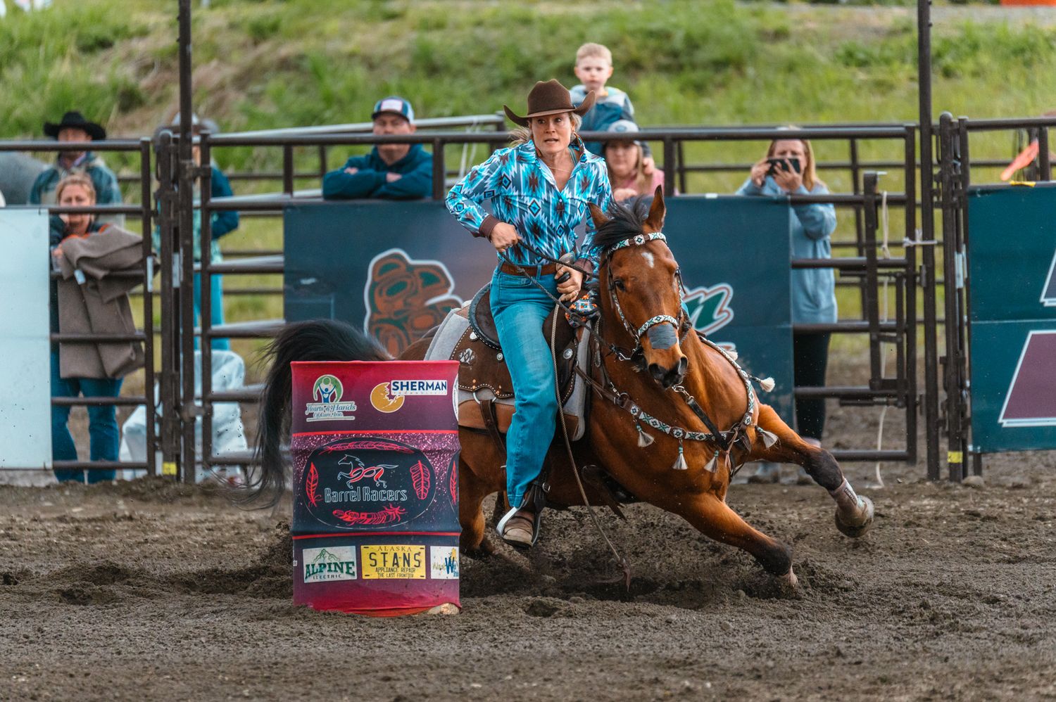 Competitive barrel racing with rider steering horse around pink barrel in arena.