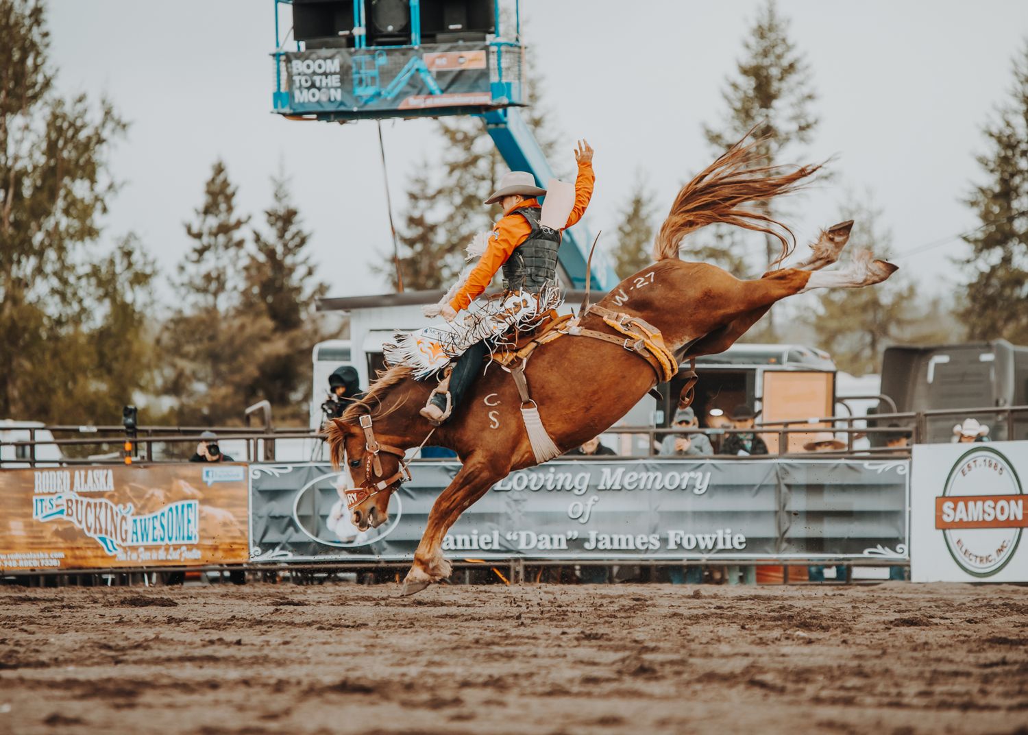 Dramatic bronc riding moment with horse and rider airborne during rodeo competition.