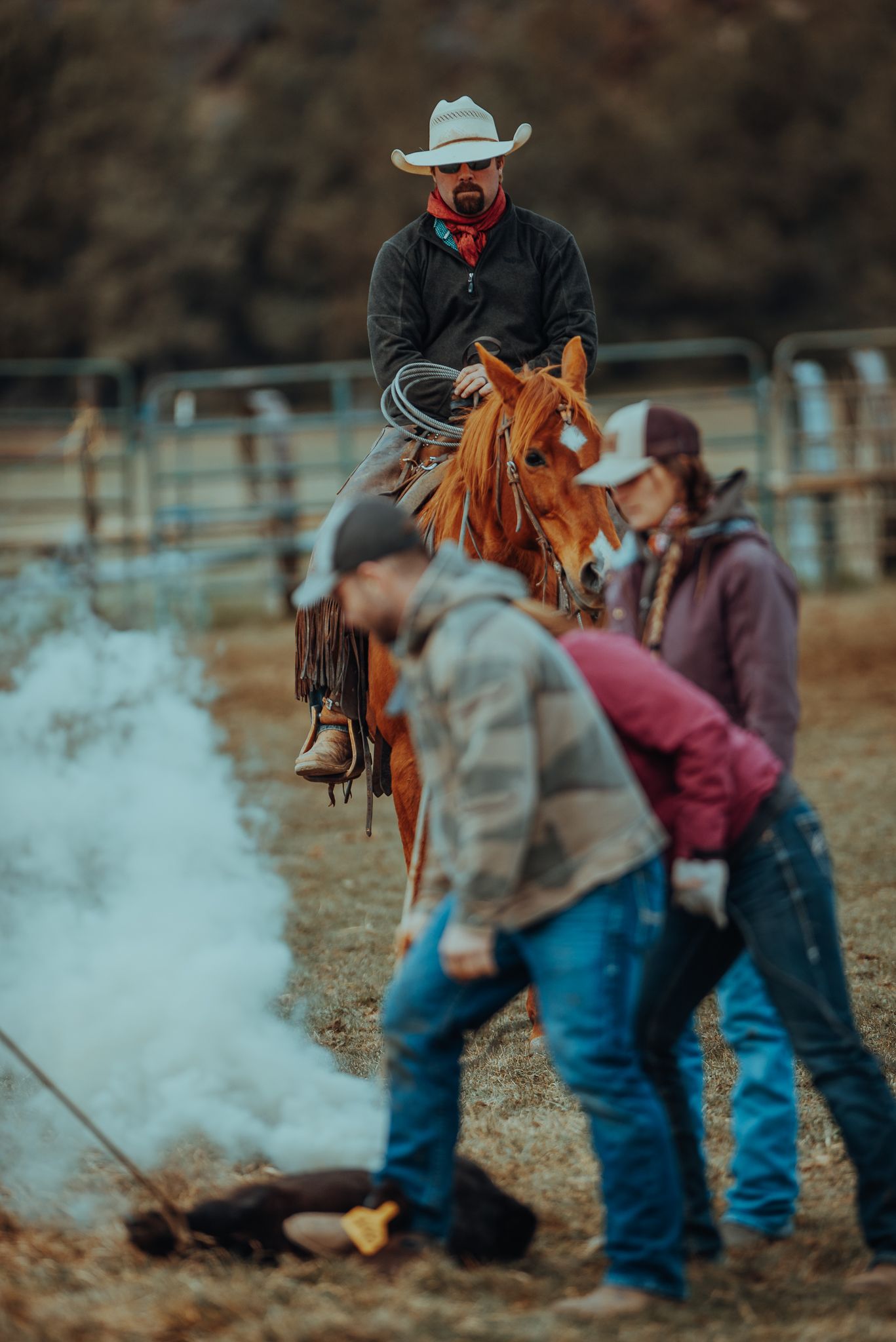 Cowboys gather around a smoky campfire during a chilly morning on the ranch.