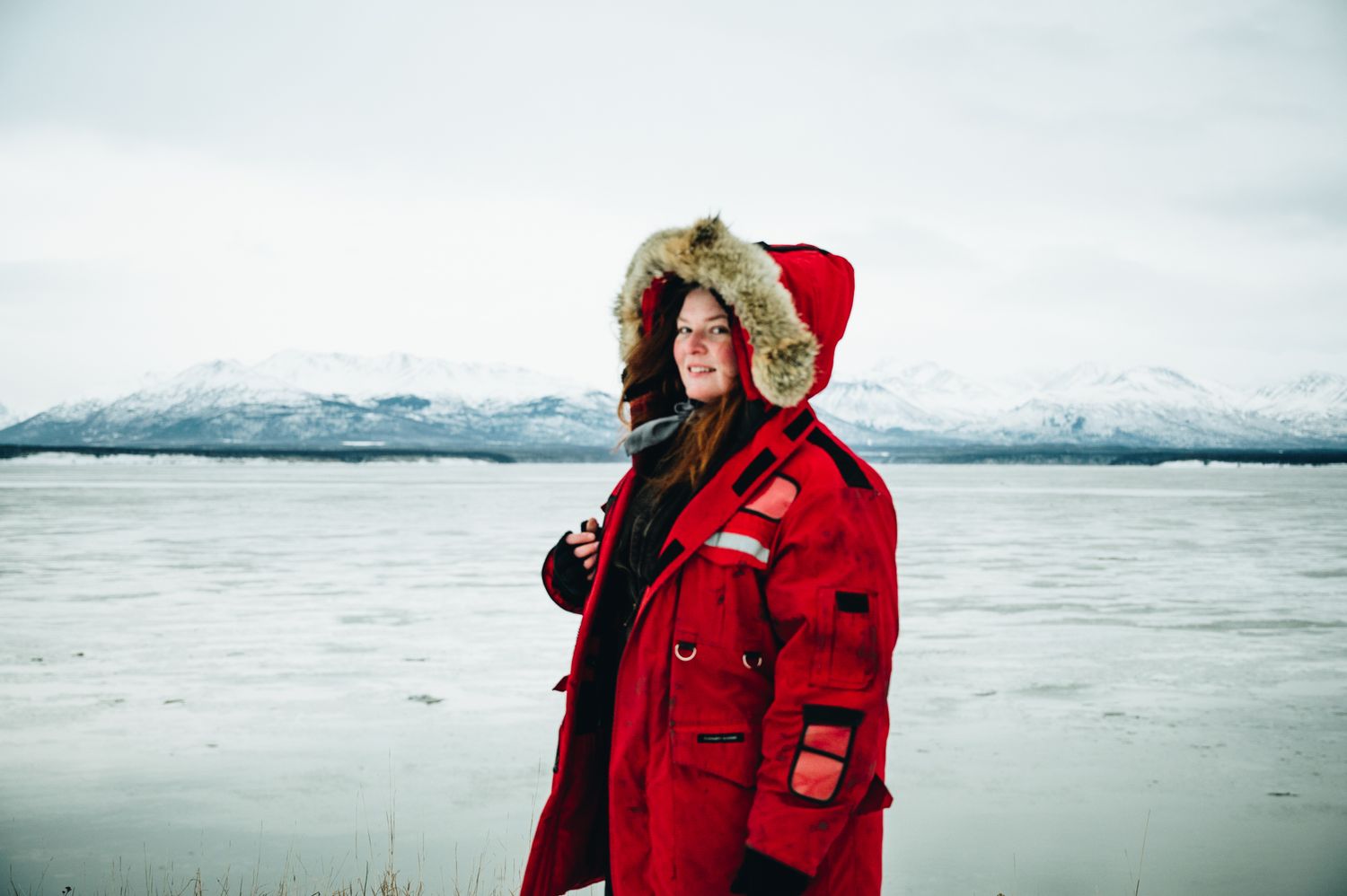 People in bright red winter parkas explore a snowy arctic landscape.