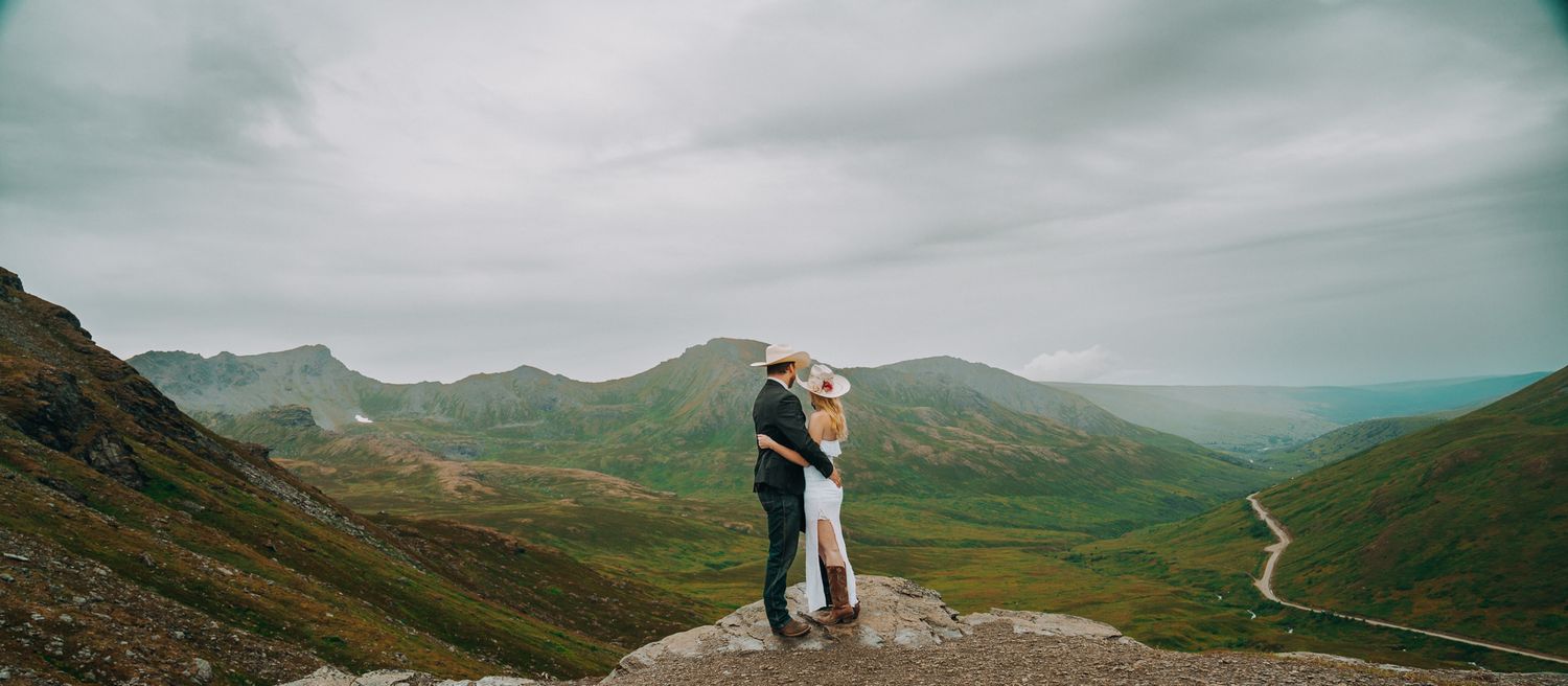 Dramatic mountain vista with winding paths and rugged terrain under moody skies.