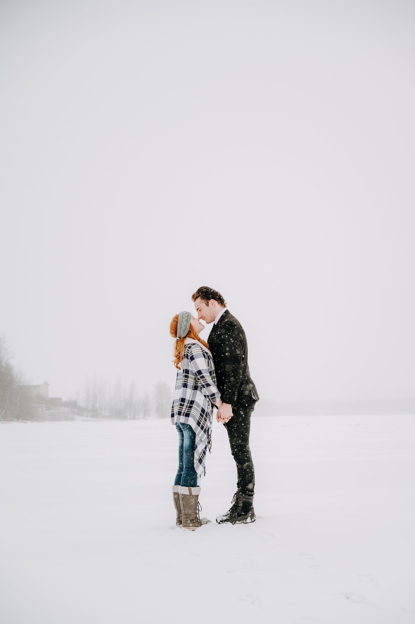 Two figures standing close together in a snowy field during winter.