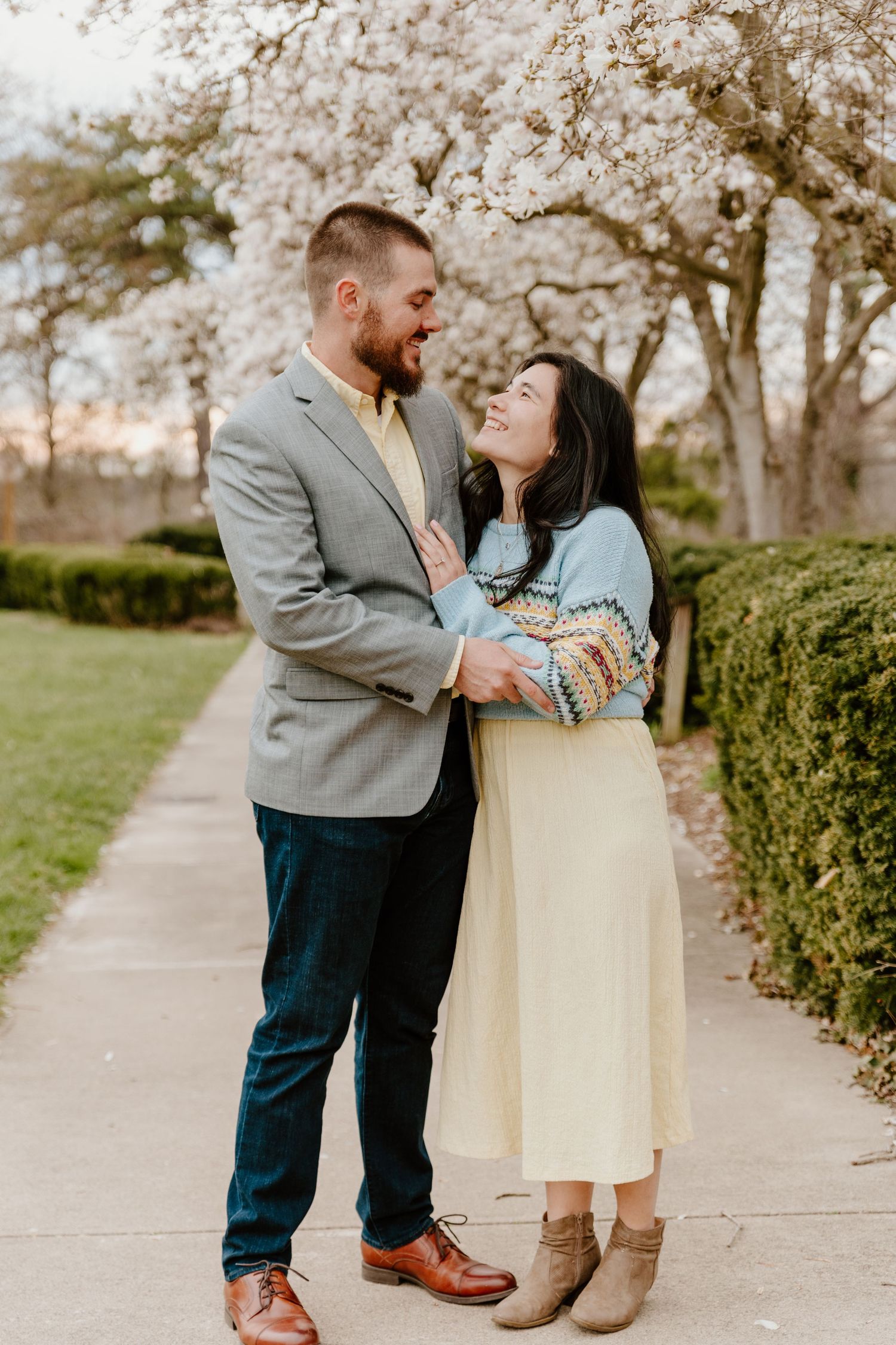 Couple sharing romantic moment under blooming cherry blossom trees in spring.