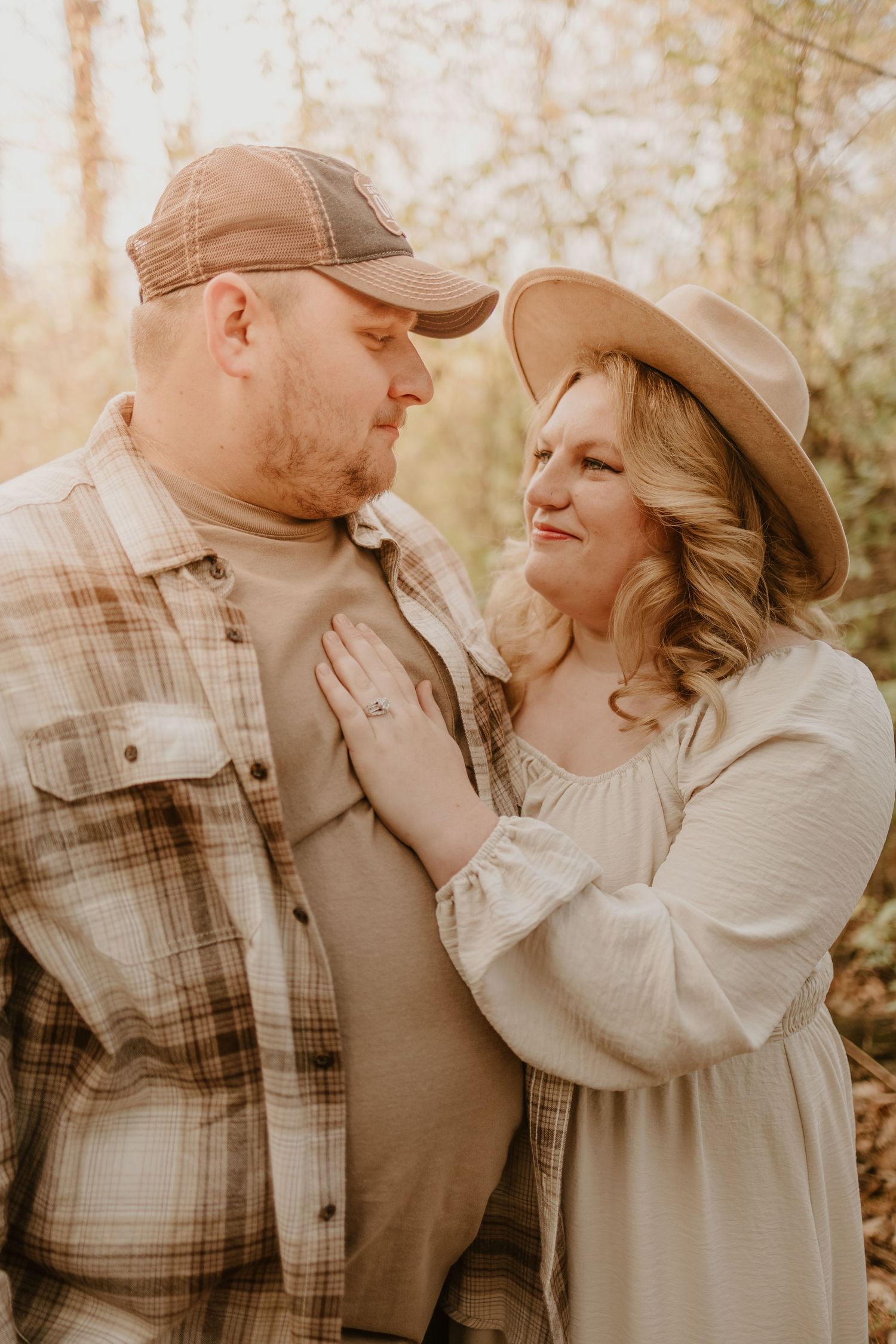 A couple shares loving moments in earth-toned clothing against a warm autumn background.