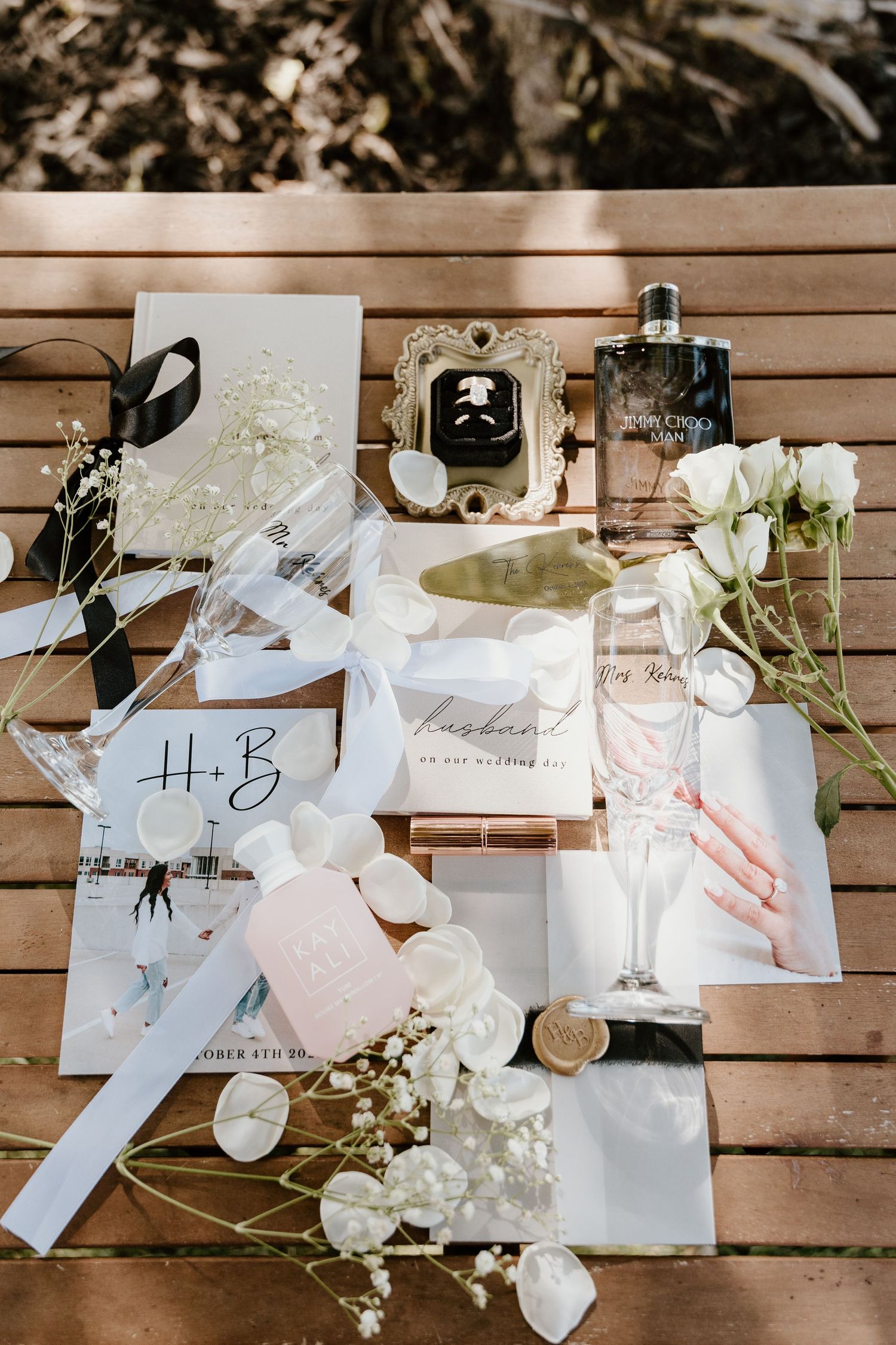 Wedding favor bags and gift boxes arranged on wooden surface with white flowers and ribbons create an elegant display.