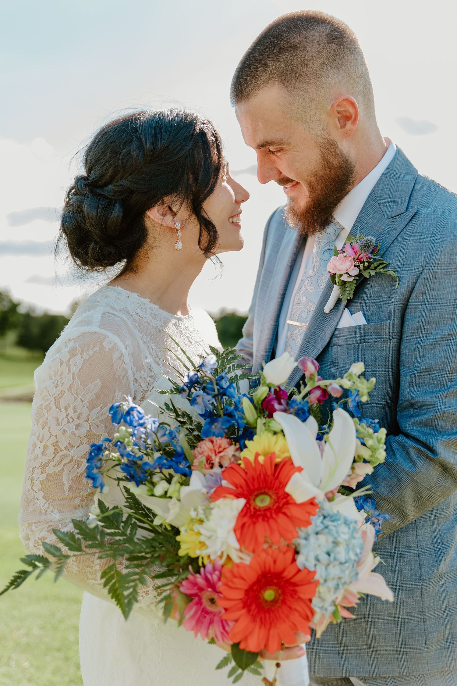A wedding couple shares an intimate moment with a vibrant coral and blue bouquet.