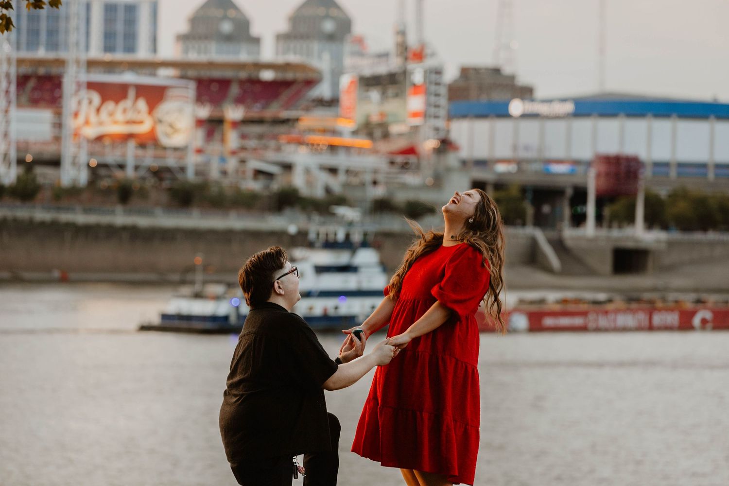A romantic proposal sequence captured against an urban waterfront backdrop.