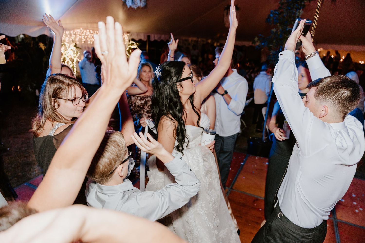 People dancing and celebrating with raised arms on a dance floor at an evening event.