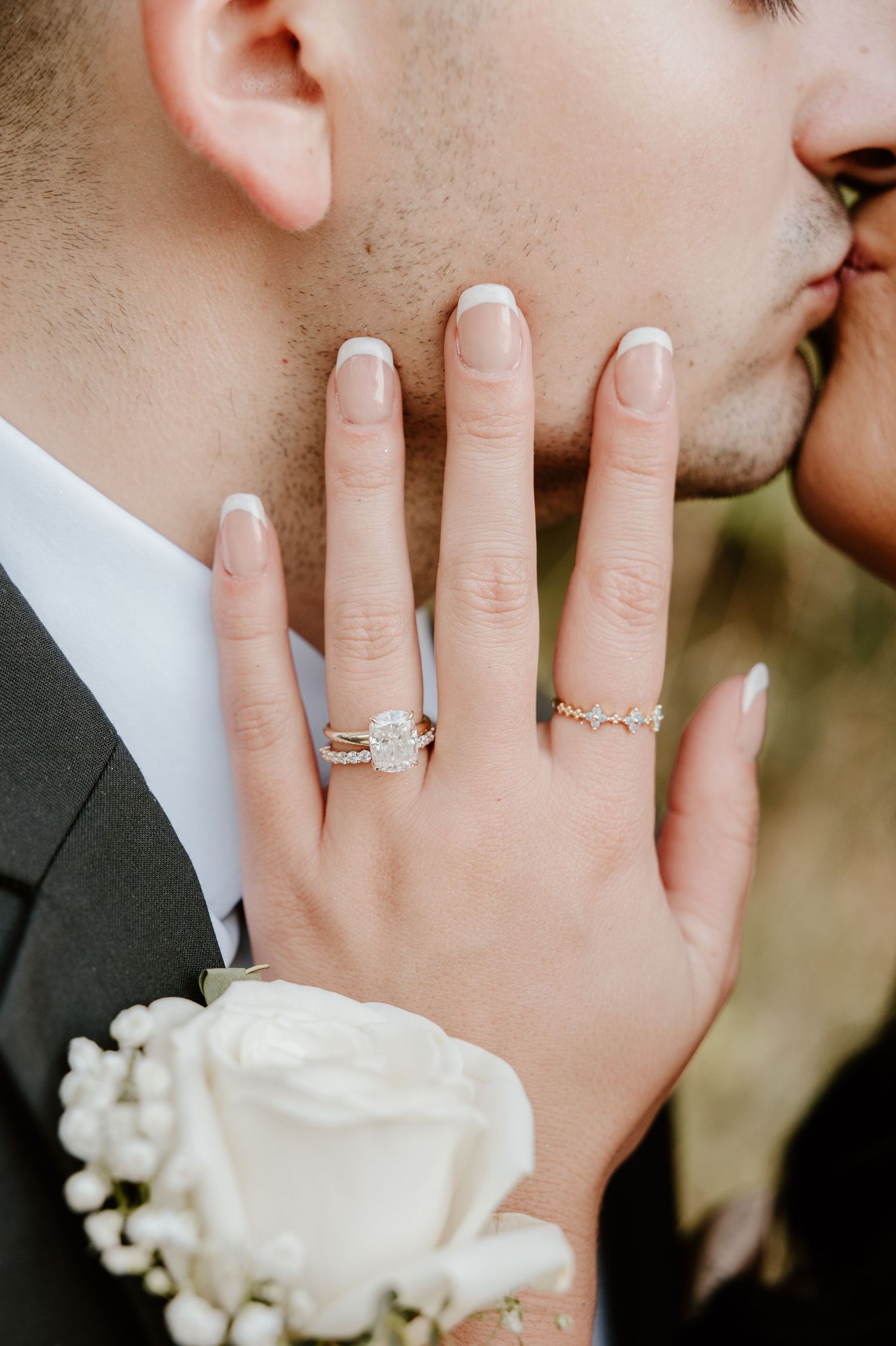 Close-up sequence of wedding rings and white rose corsage on hands during an intimate romantic moment.