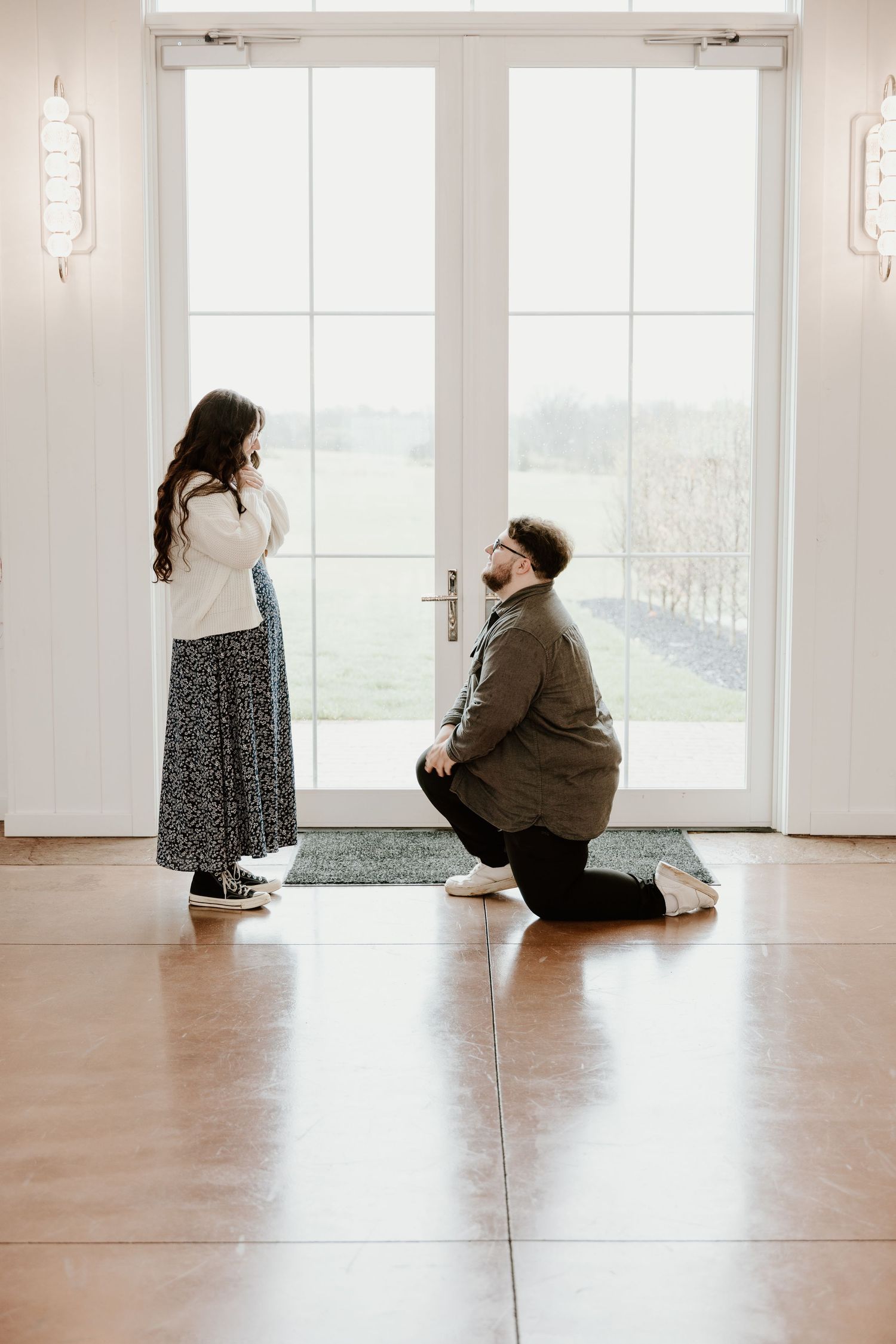 A minimalist indoor photoshoot with couples sitting on a bright white floor.