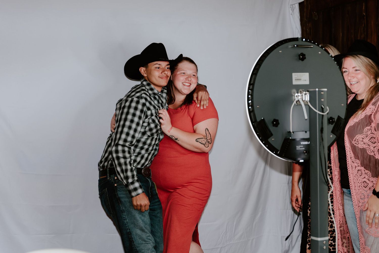 People having fun posing and laughing together at a photo booth session with studio lighting equipment.