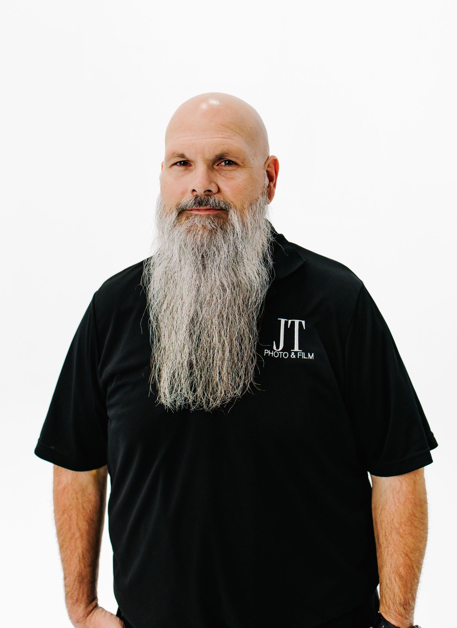 A bald man with a long grey beard wearing a black t-shirt shown from different angles against a white background.