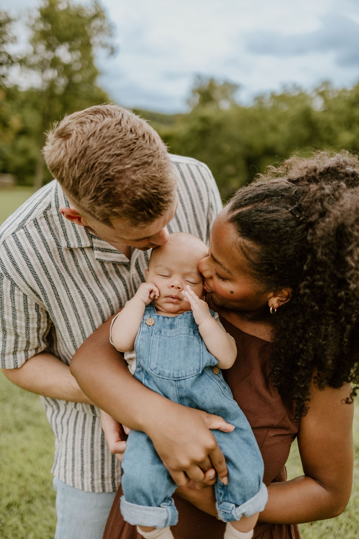 Sweet family moment captured outdoors with toddler in denim overalls.