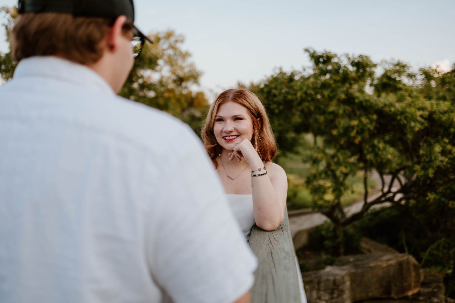 A romantic outdoor photoshoot moment at sunset with a white dress and casual attire.