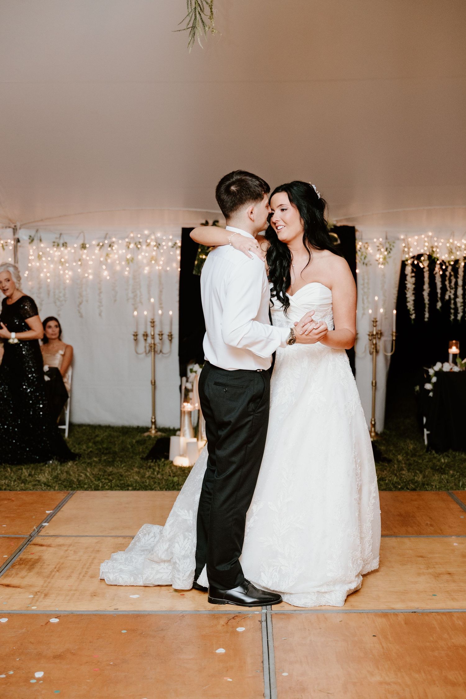 A romantic first dance sequence at a wedding reception with twinkle lights and white decor in the background.