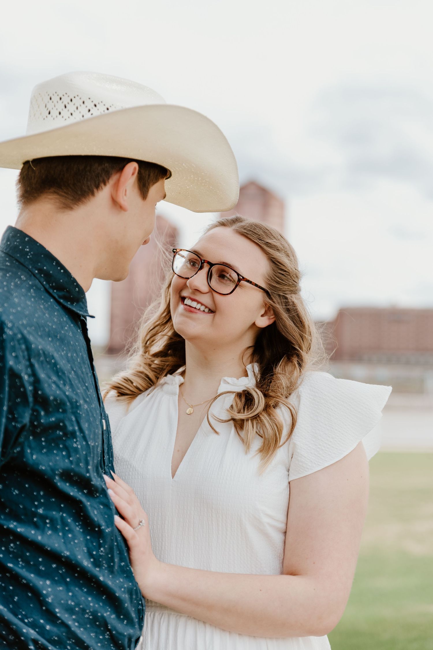 Couple sharing intimate moment outdoors with white hat and spring attire.