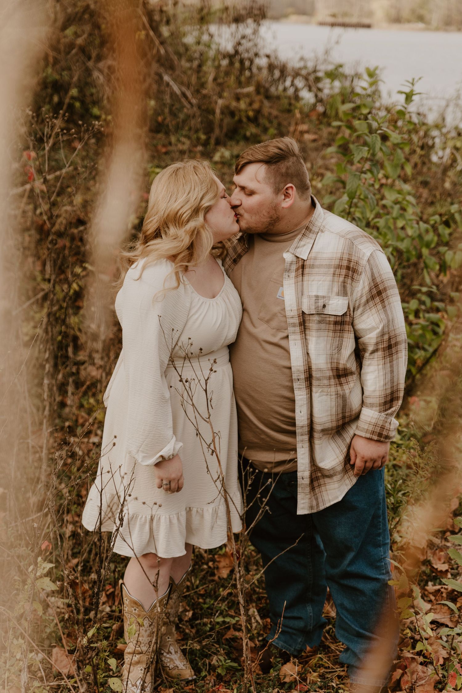 A couple embraces tenderly in a romantic outdoor photoshoot with natural autumn foliage.