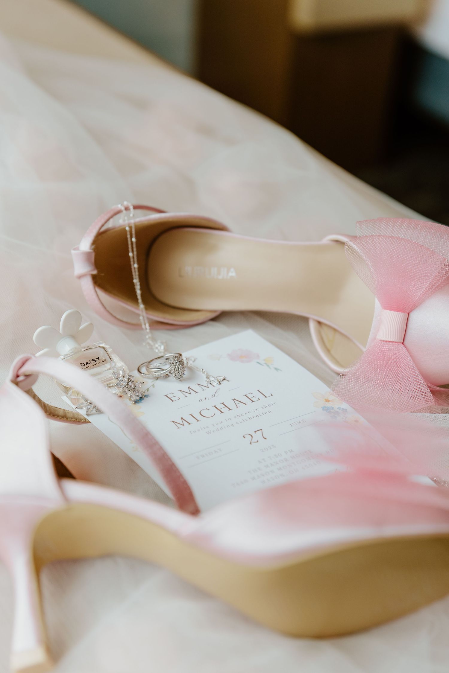 Close-up view of elegant wedding invitations with pink ribbon details and delicate calligraphy in soft lighting.
