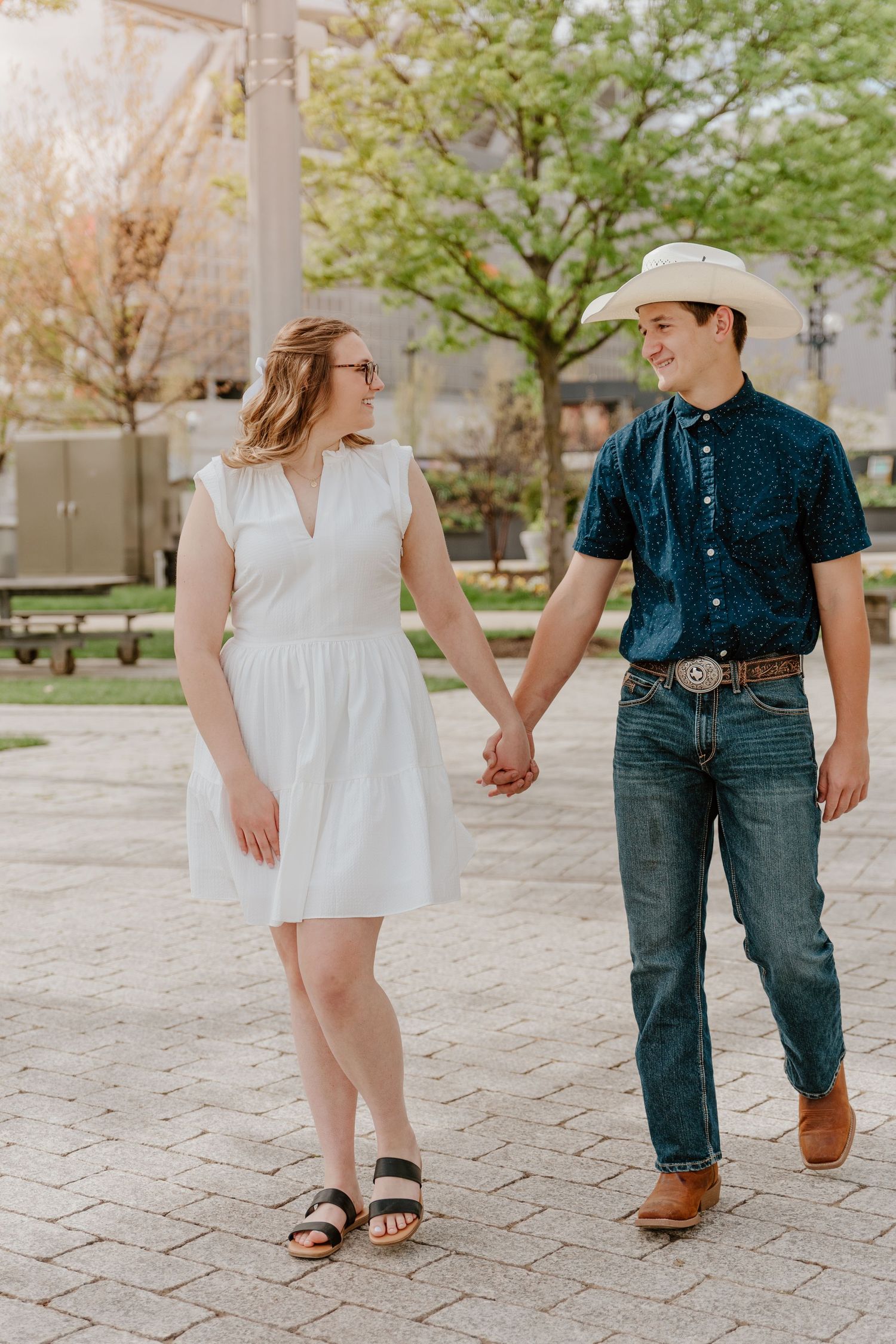 Couple in casual spring outfits walking together on decorative stone pathway.