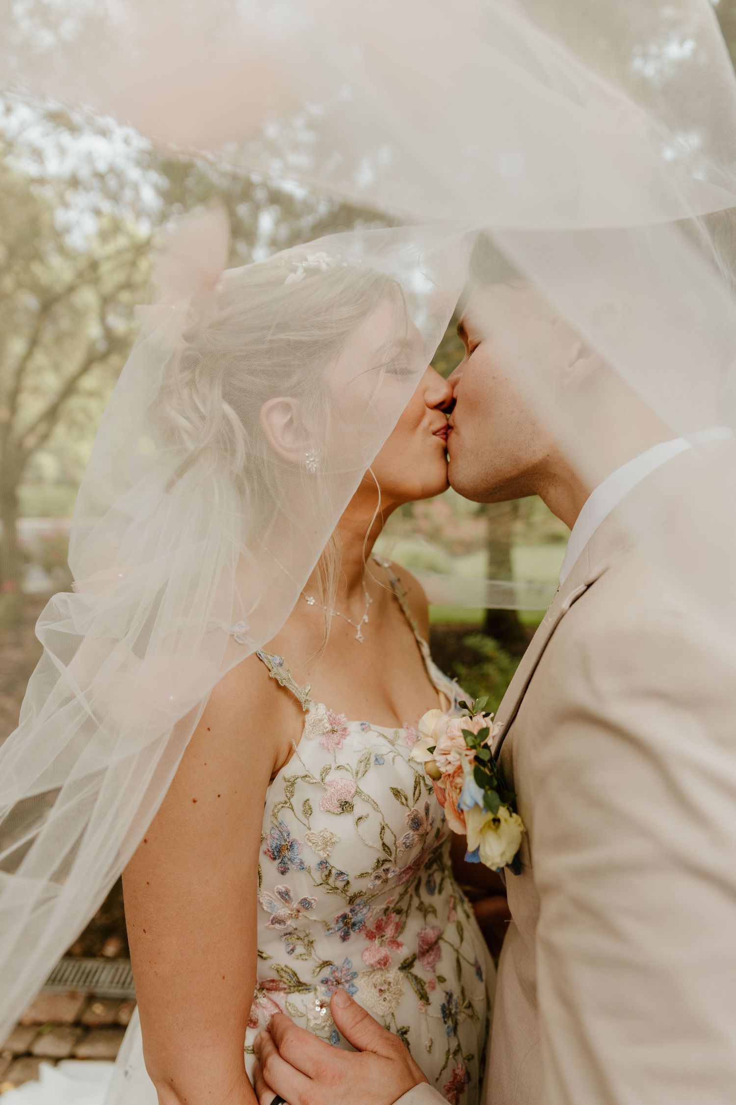 Romantic moment under bridal veil with soft natural lighting in garden setting.