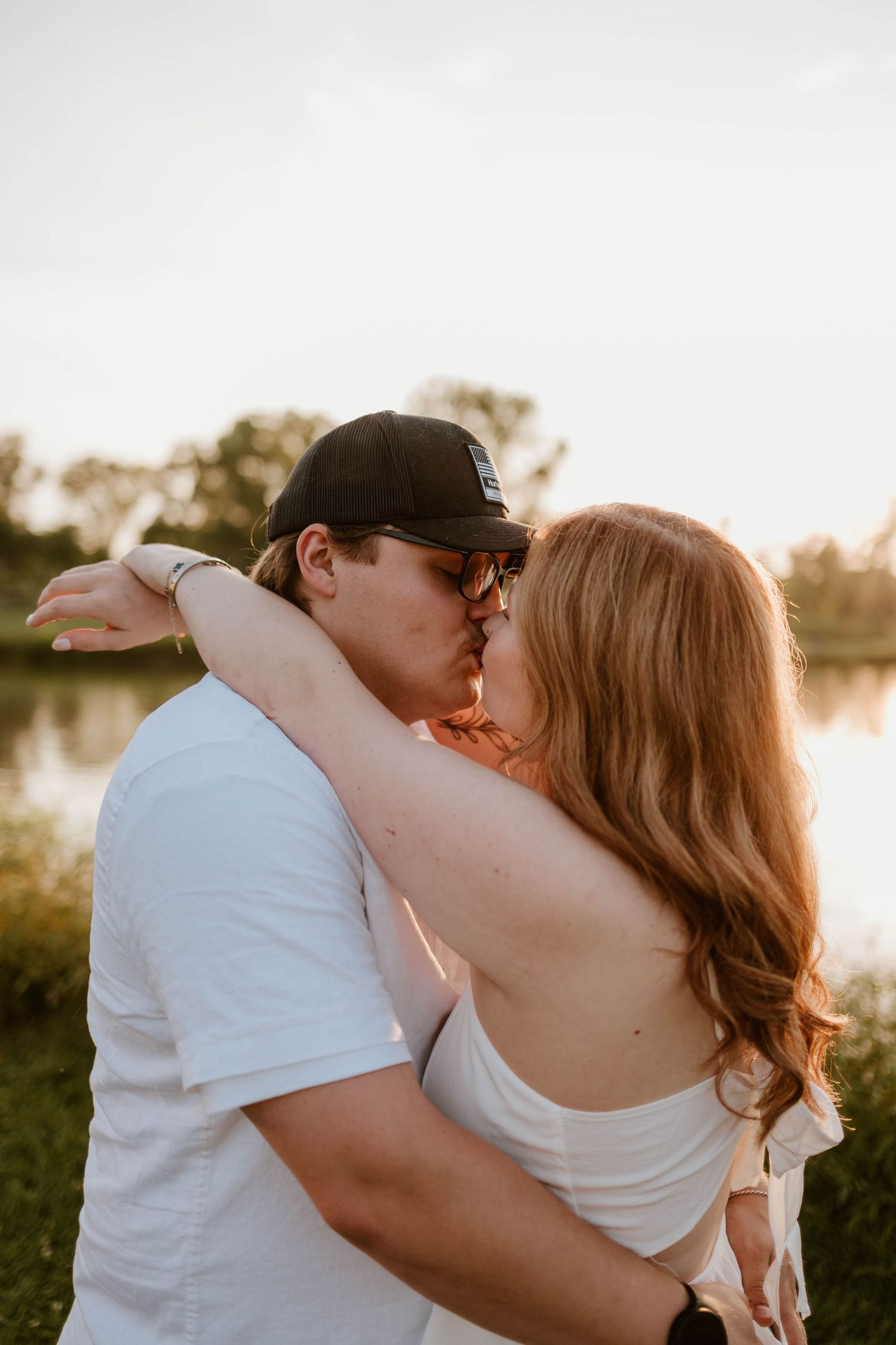 Intimate sunset moment captured by a lake with white summer outfits.