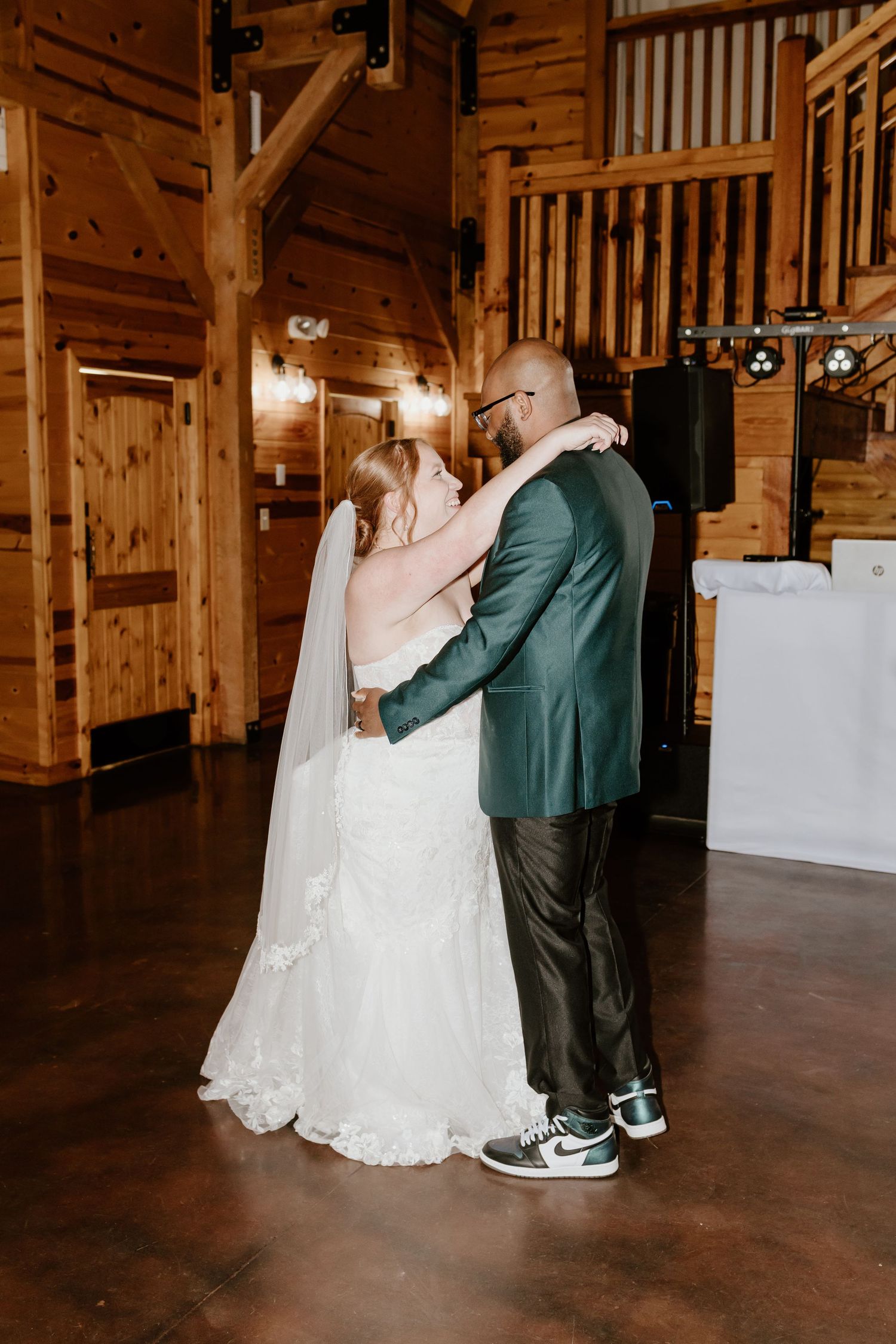 A couple dances together in a rustic wooden barn venue during their first dance at their wedding celebration.