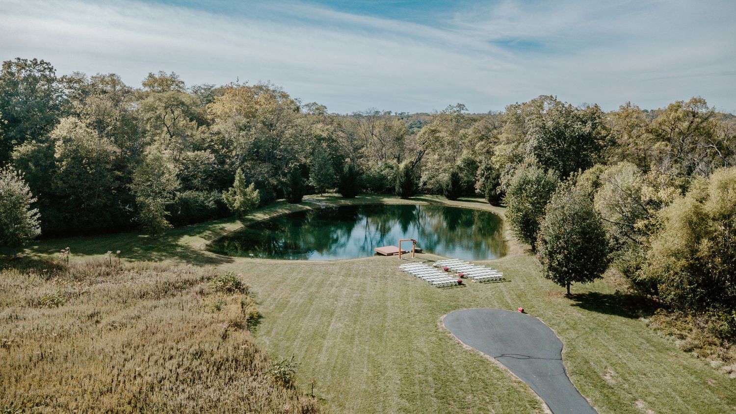 A panoramic view of a winding path through a green golf course with mature trees and blue sky.