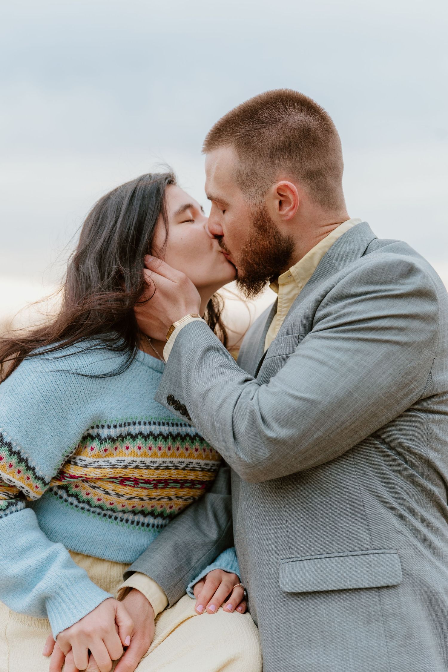 Intimate moment shared between couple wearing grey suit and blue sweater.