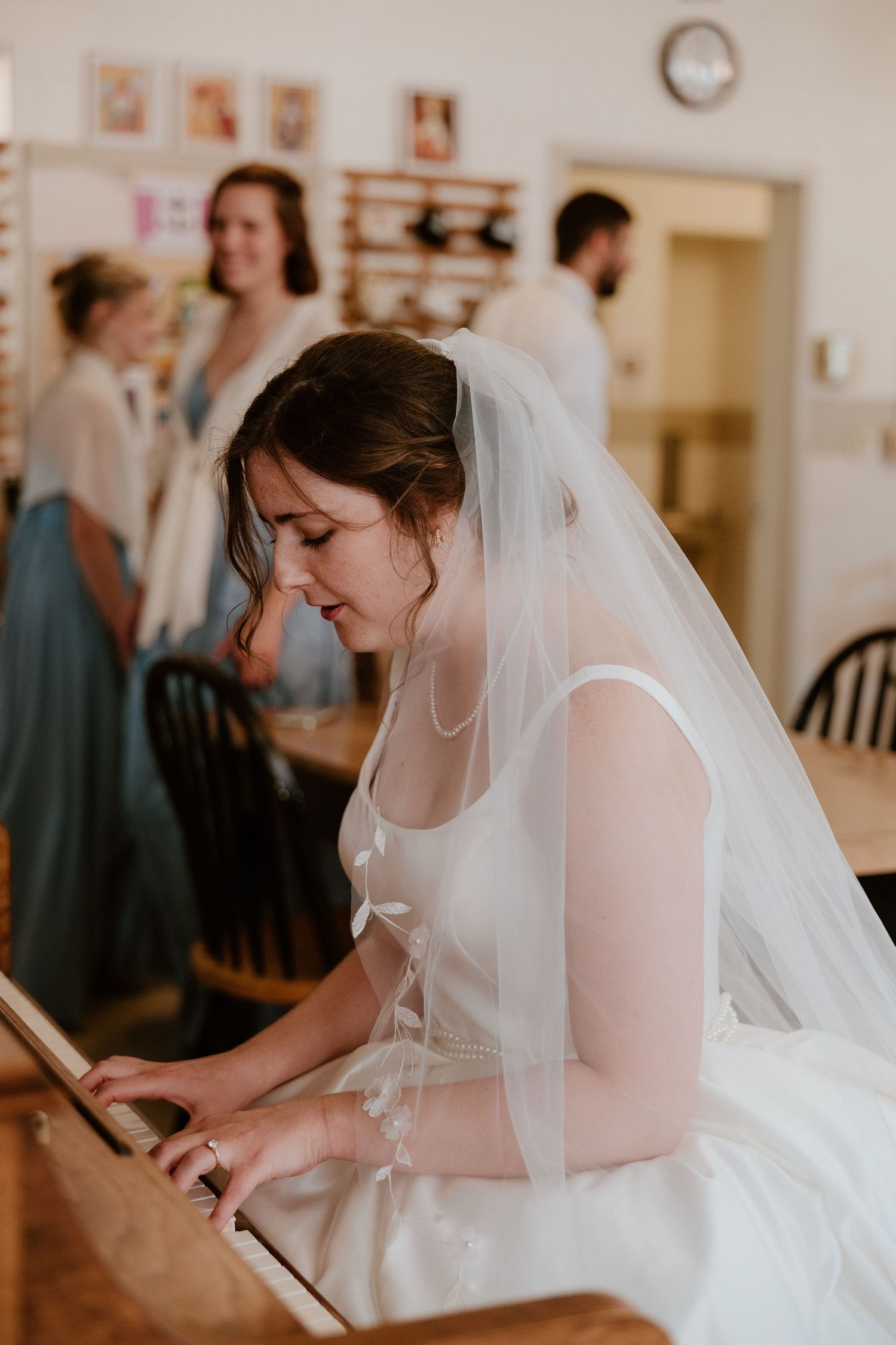 A bride in a white wedding dress and veil writes or signs documents during her wedding preparations.