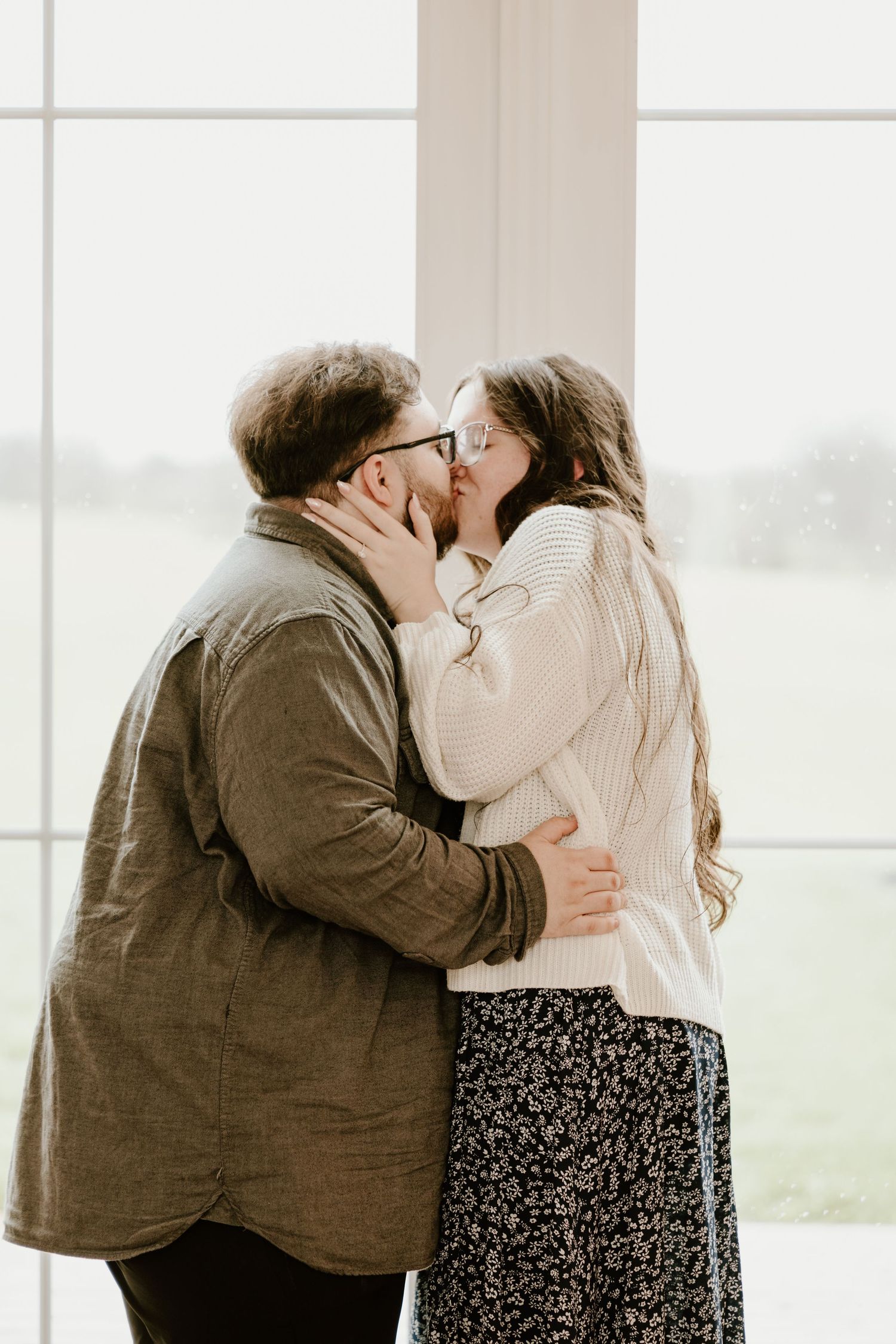 A romantic couple shares intimate kisses in front of a bright window in a sequence of tender moments.