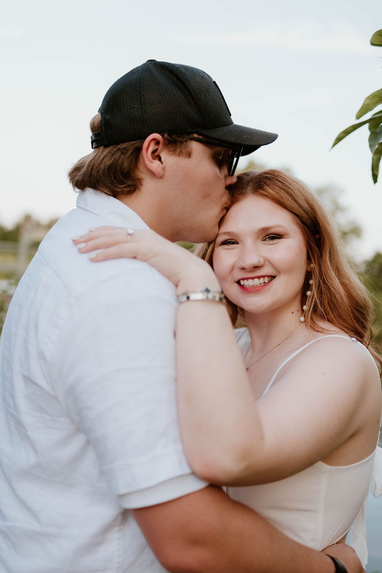 A casual romantic portrait showing a close embrace against a bright background.