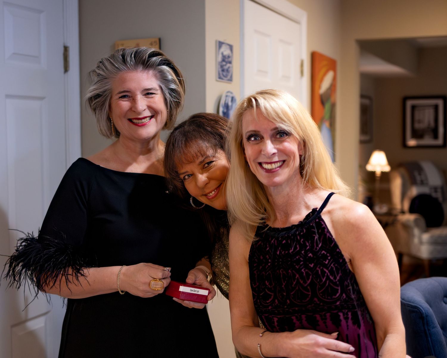 A group of people in formal attire sharing laughter and embraces at a social gathering.
