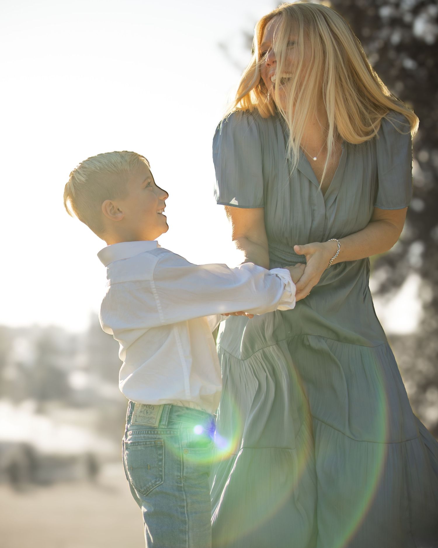 A mother and child share a tender moment together in soft sunlit backlighting creating a dreamy silhouette.