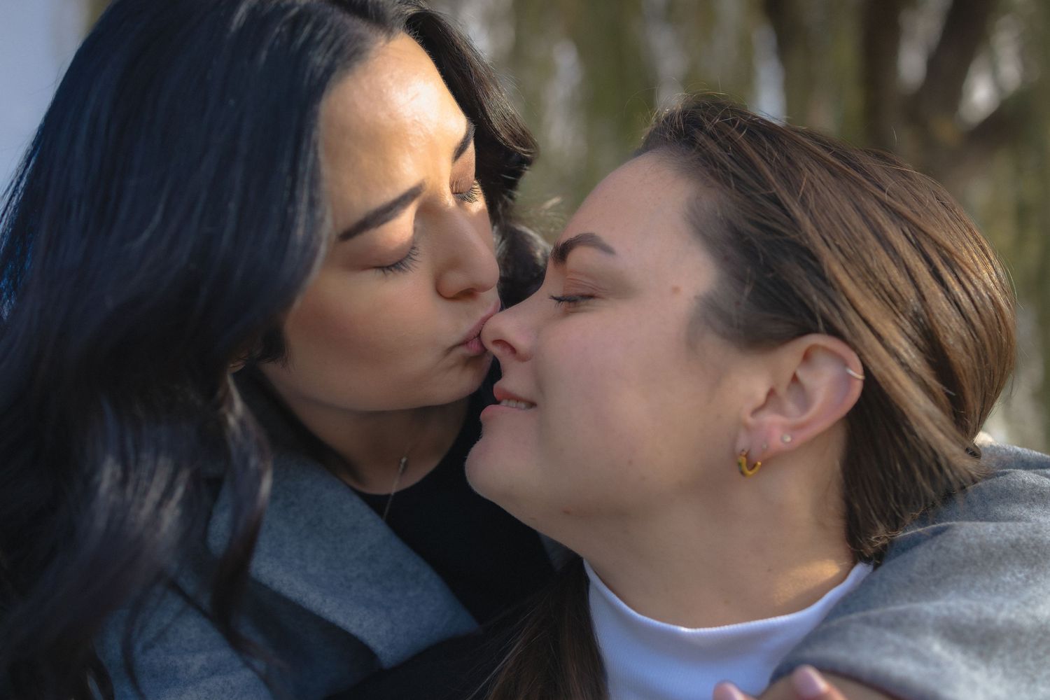 A couple sharing a romantic kiss outdoors in a sequence of seven similar photographs.