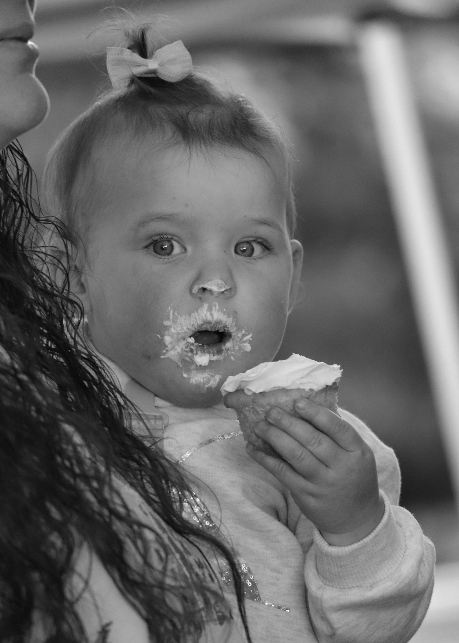 Black and white photo of a small child with messy frosting on their face while eating cake.