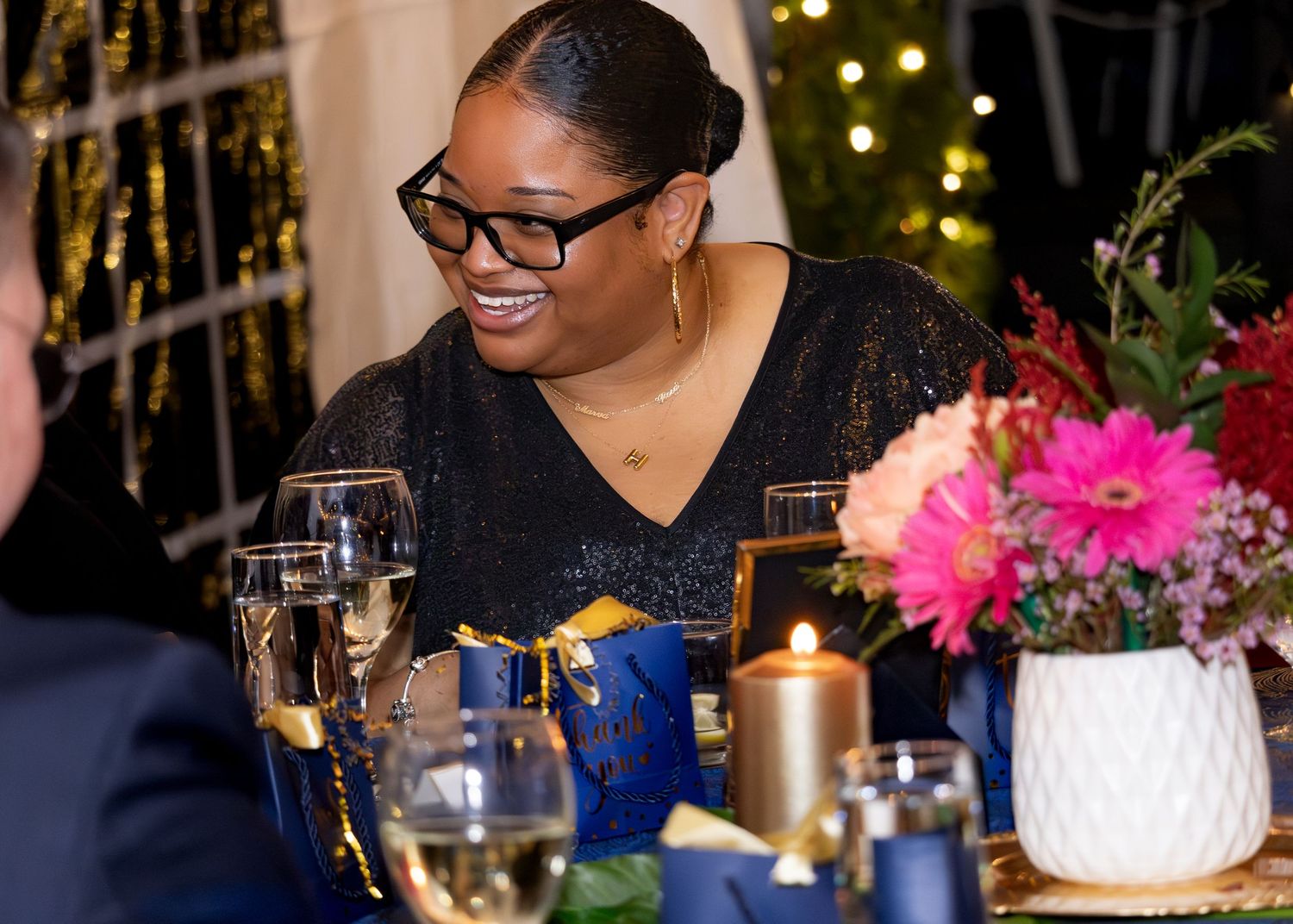 A candlelit dinner table decorated with pink flowers and glassware for an elegant evening celebration.