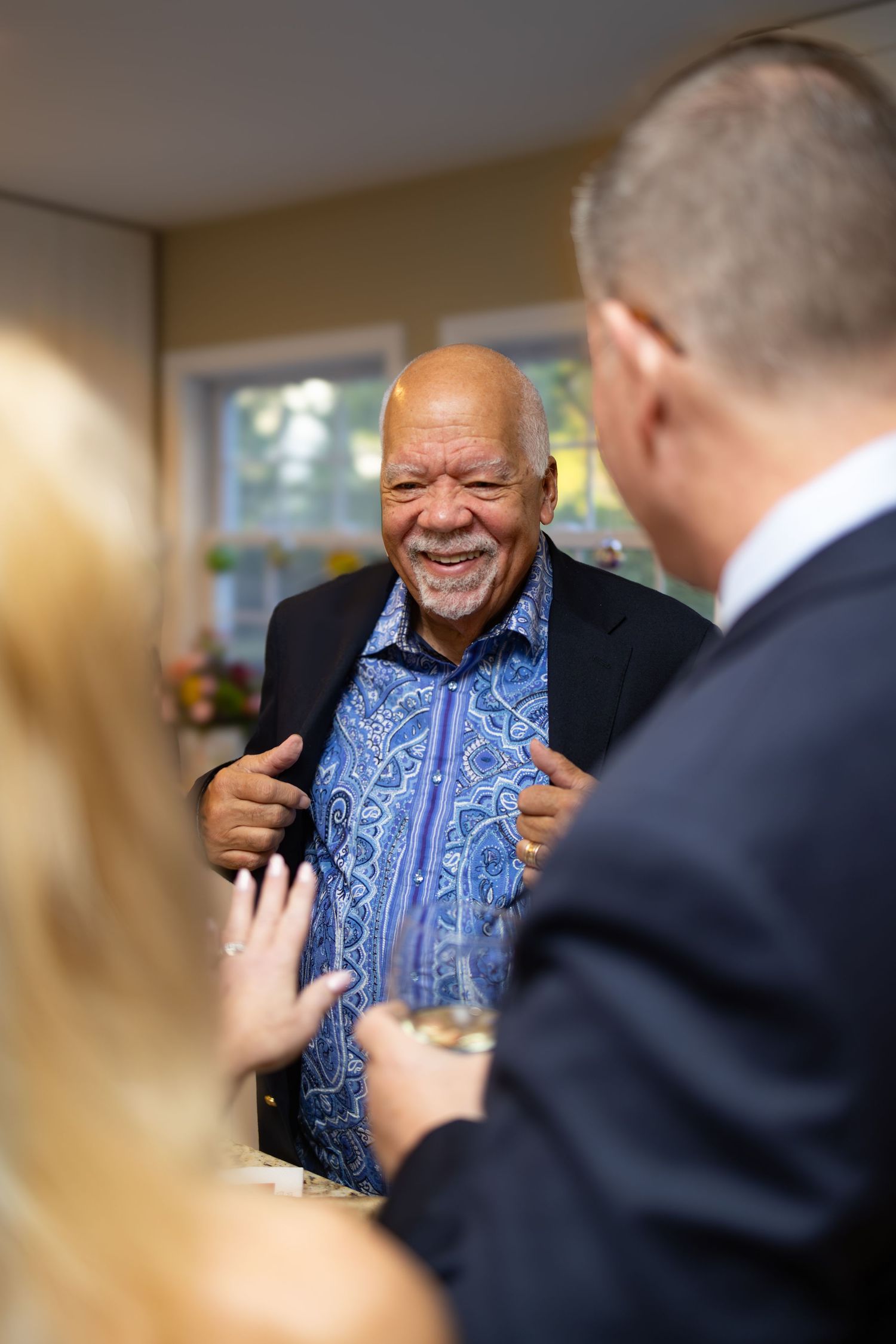 A series of candid shots showing someone wearing a blue patterned shirt in conversation with others in an indoor setting.
