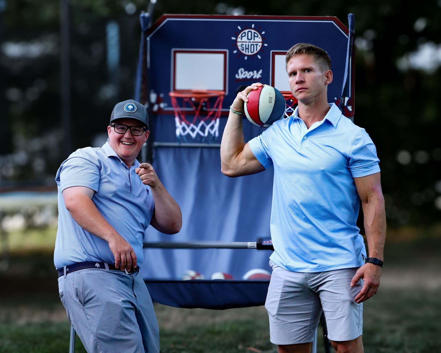 Group of people in blue and white playing basketball outside at a sports event with a red and white ball.
