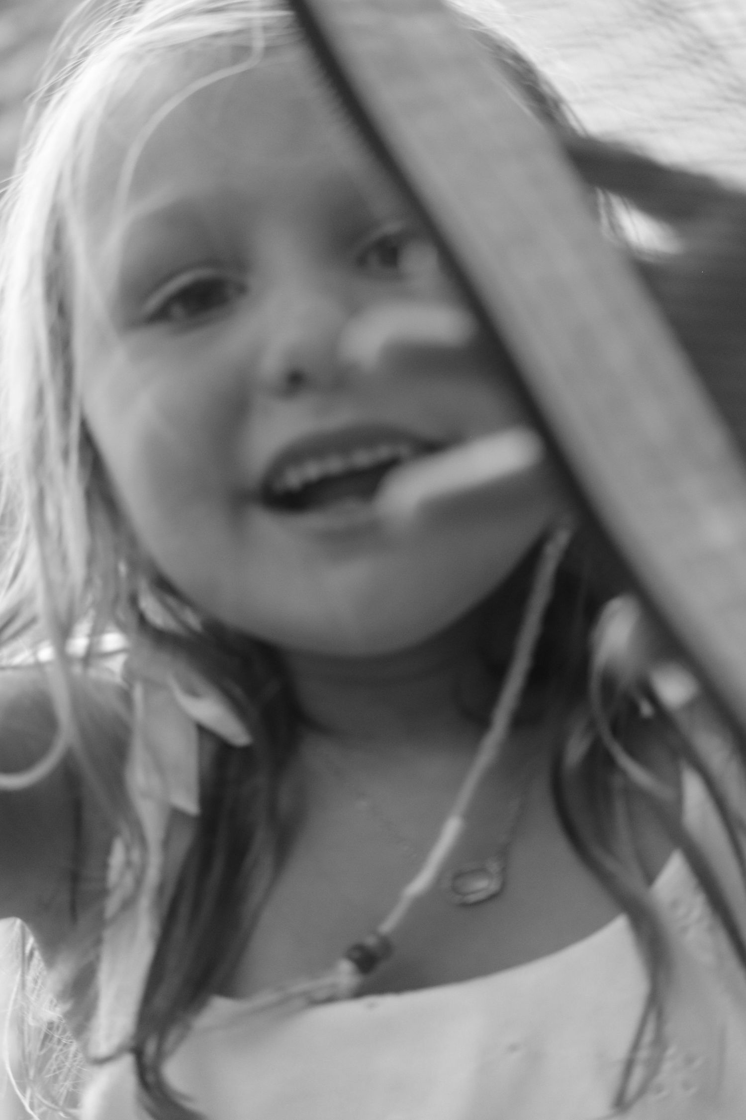 A black and white close-up portrait shows a child smiling with light hair while playing outdoors.