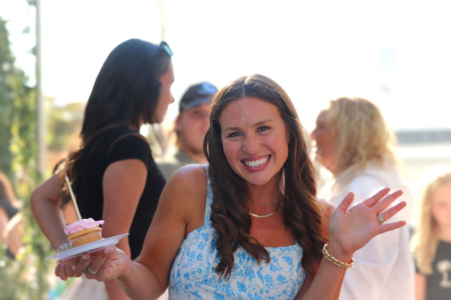 Happy guests socialize and celebrate at an outdoor summer party with natural lighting.
