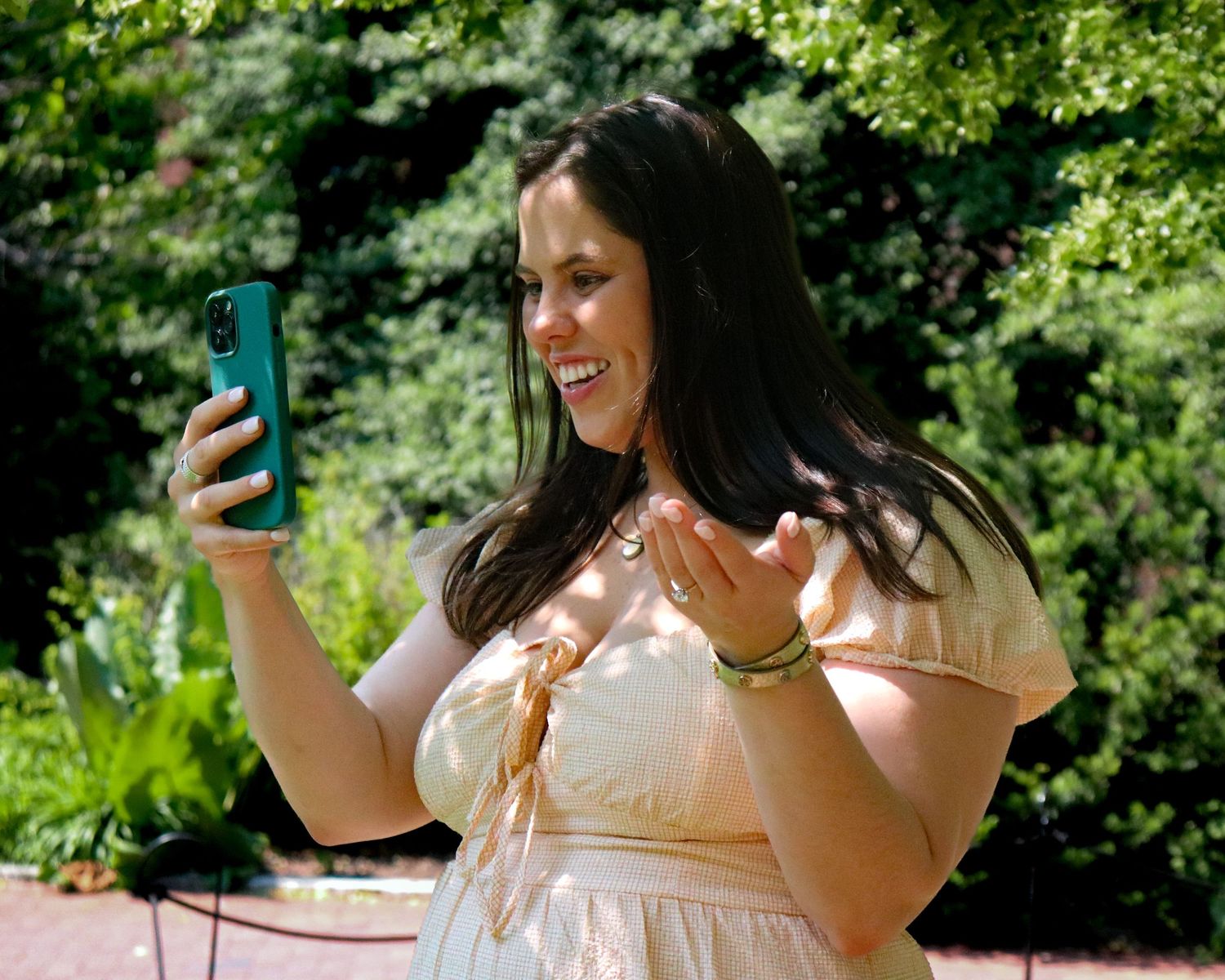 Bride-to-be laughing in pink dress during Smithsonian Castle engagement session in DC garden.
