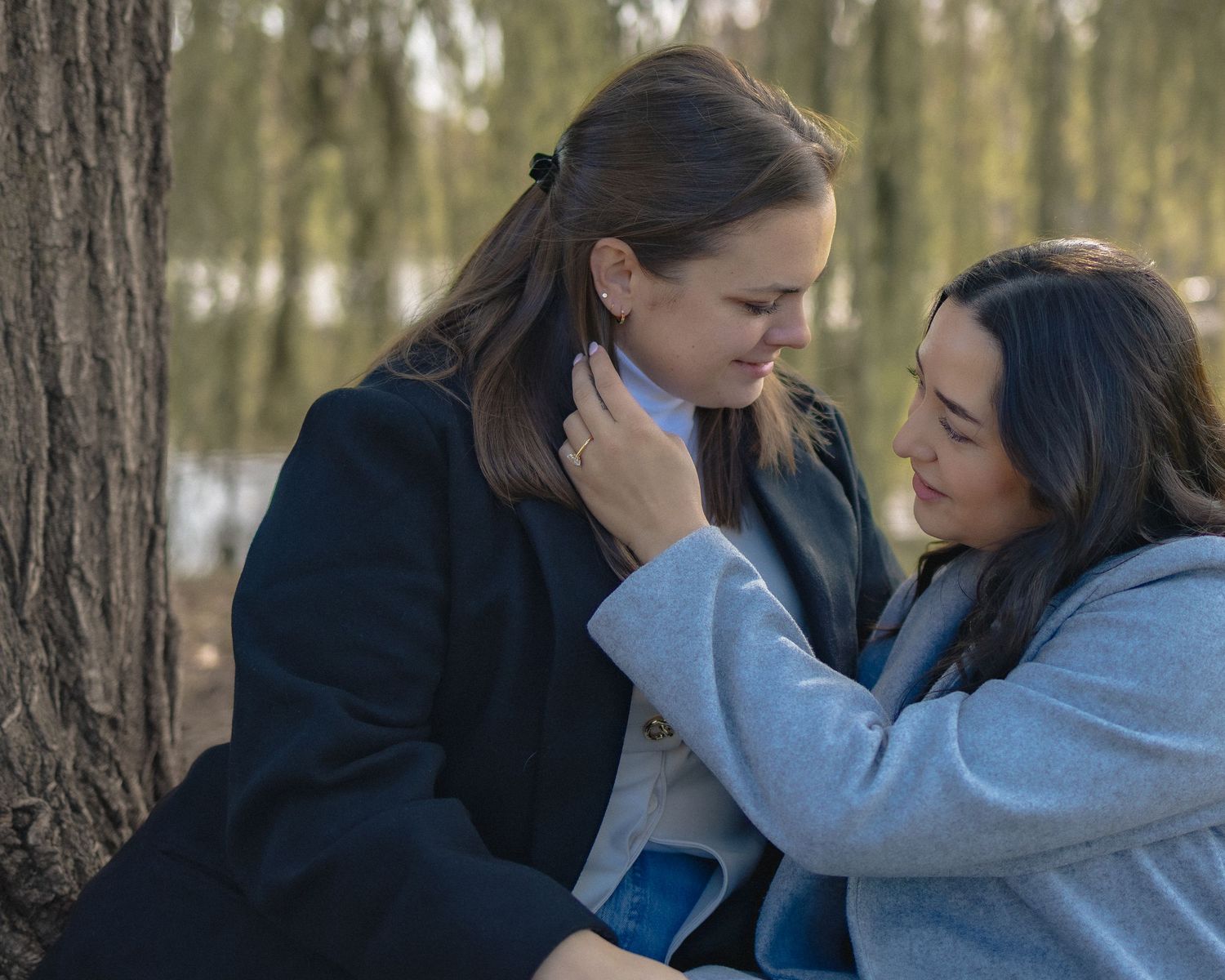 A tender emotional moment between two people embracing in a wooded forest setting.