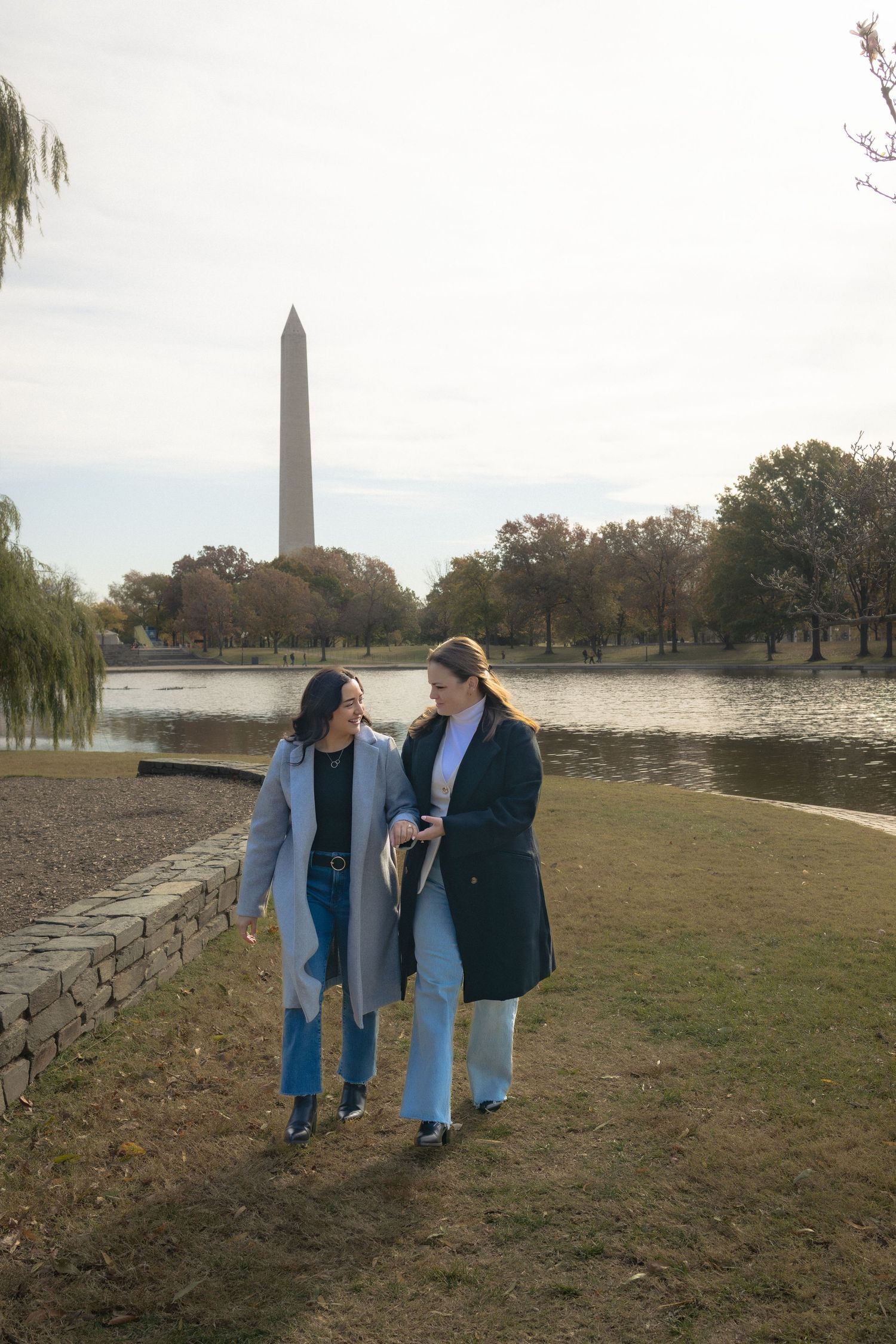 Couple walking and talking along the waterfront path near the Washington Monument on an autumn day.